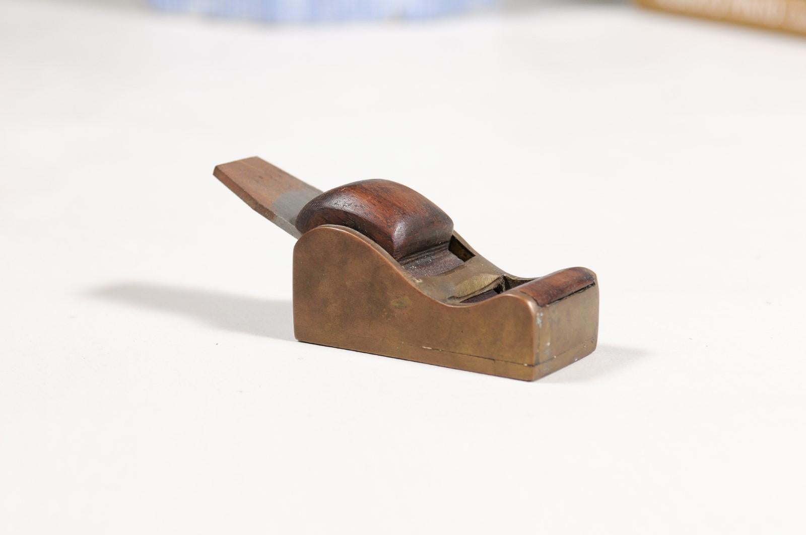 An English Victorian period carpenter's woodworking hand planer from the late 19th century, with brass structure, wood handle and metal blade. Created in England during the later years of Queen Victoria's reign in the 19th century, this woodworking
