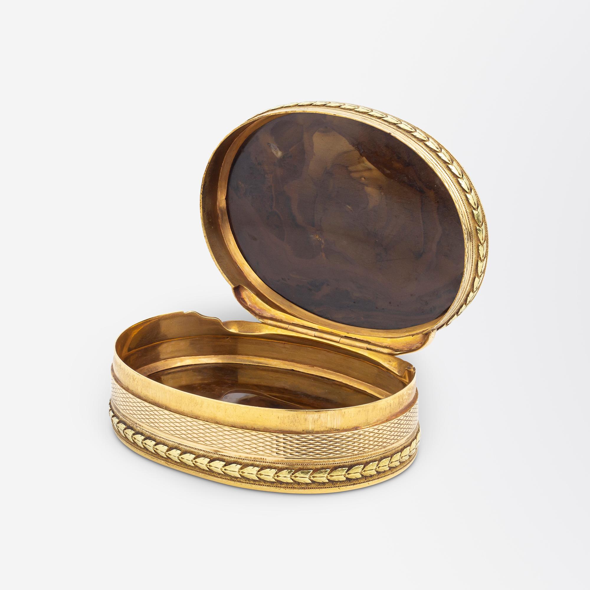 This rare and exceedingly beautiful snuff box dates to the second half of the 18th Century and was likely made in England. The oval box is crafted from 18 karat yellow and rose gold and has been set with two pieces of petrified wood agate. The lid