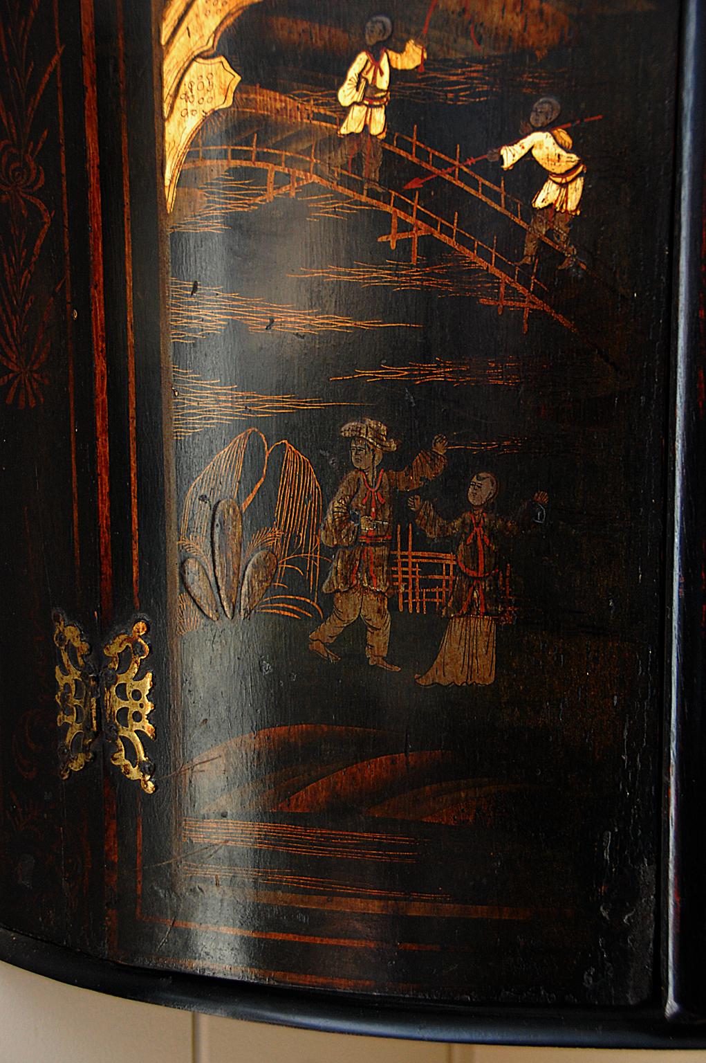 English 18th century chinoiserie decorated hanging bowfronted corner cupboard with shaped interior shelves. The original decoration has many hand painted scenes, among them: young men fishing-one with a spear the other with a rod-from an arched