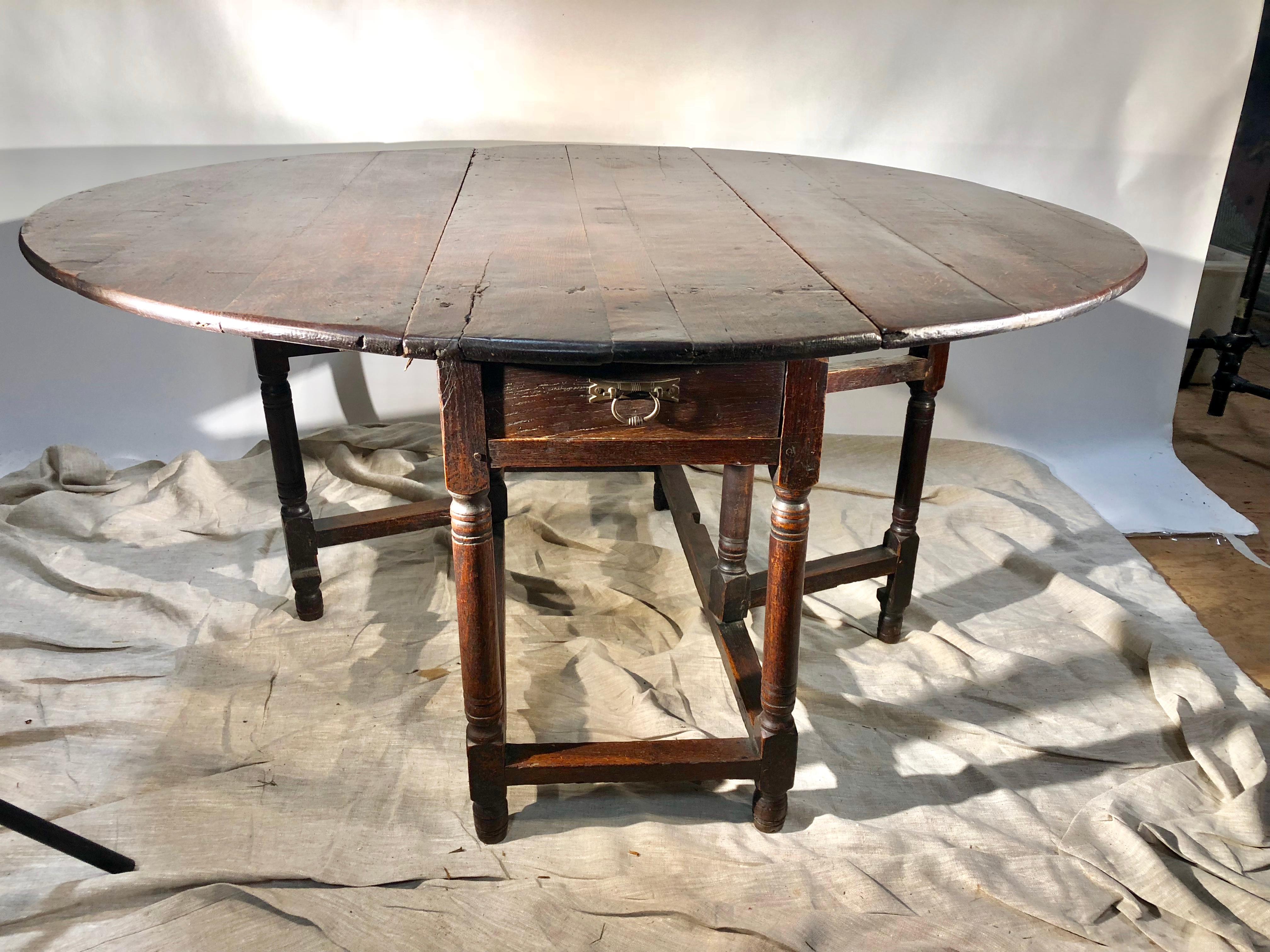 A charming gate-leg table with a large oval top, and nicely turned legs, mid-18th century English. Small drawer in one end and scalloped apron on other. Many old repairs to top give the table real charm, circa 1760.
17