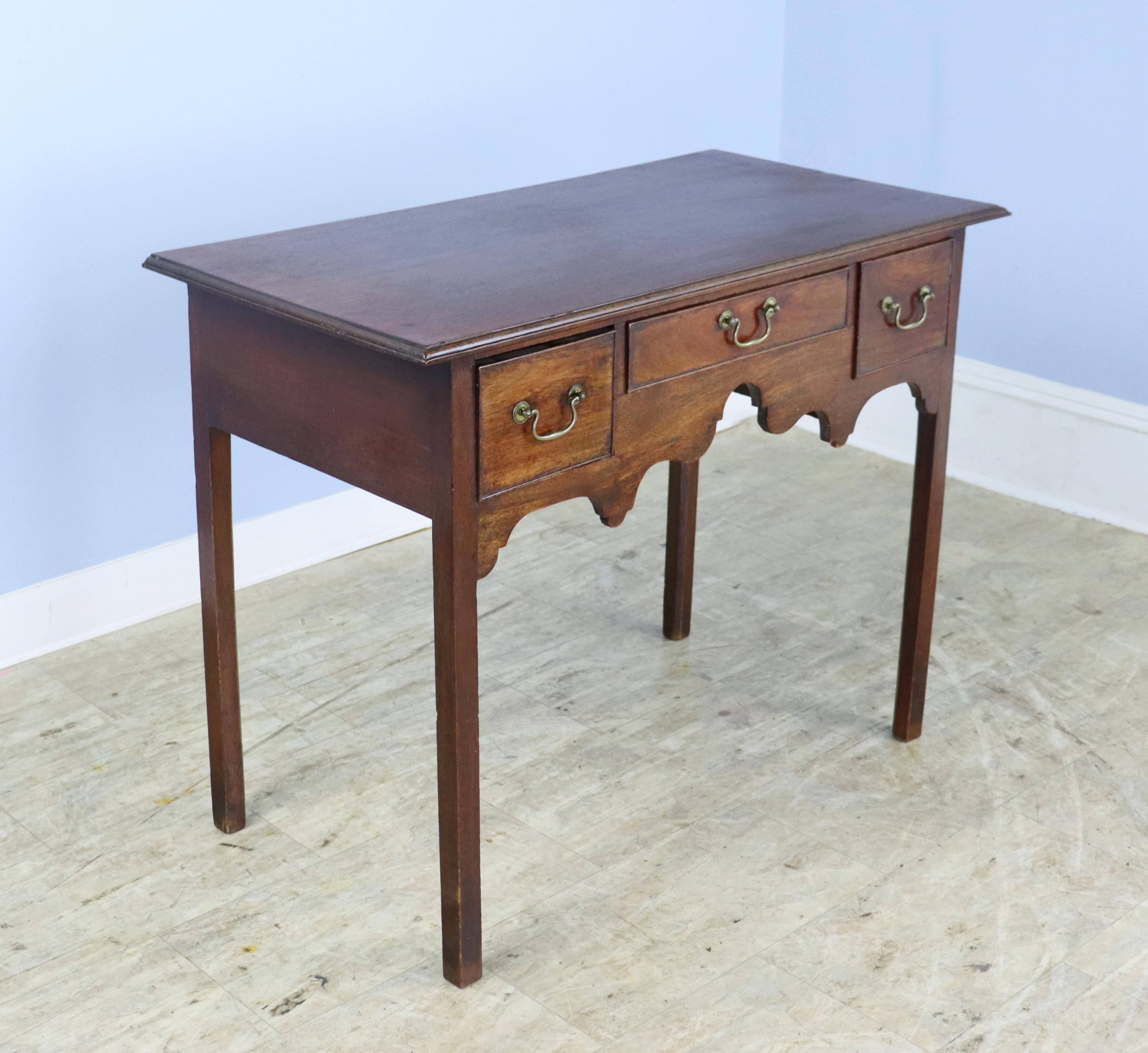 A stunning Classic period lowboy or side table with lovely fanciful aprons. Three front drawers with beautiful cockbeading in ghood condition. The top has a very handsome molding around the edge, and the base is comprised of elegantly slender legs.