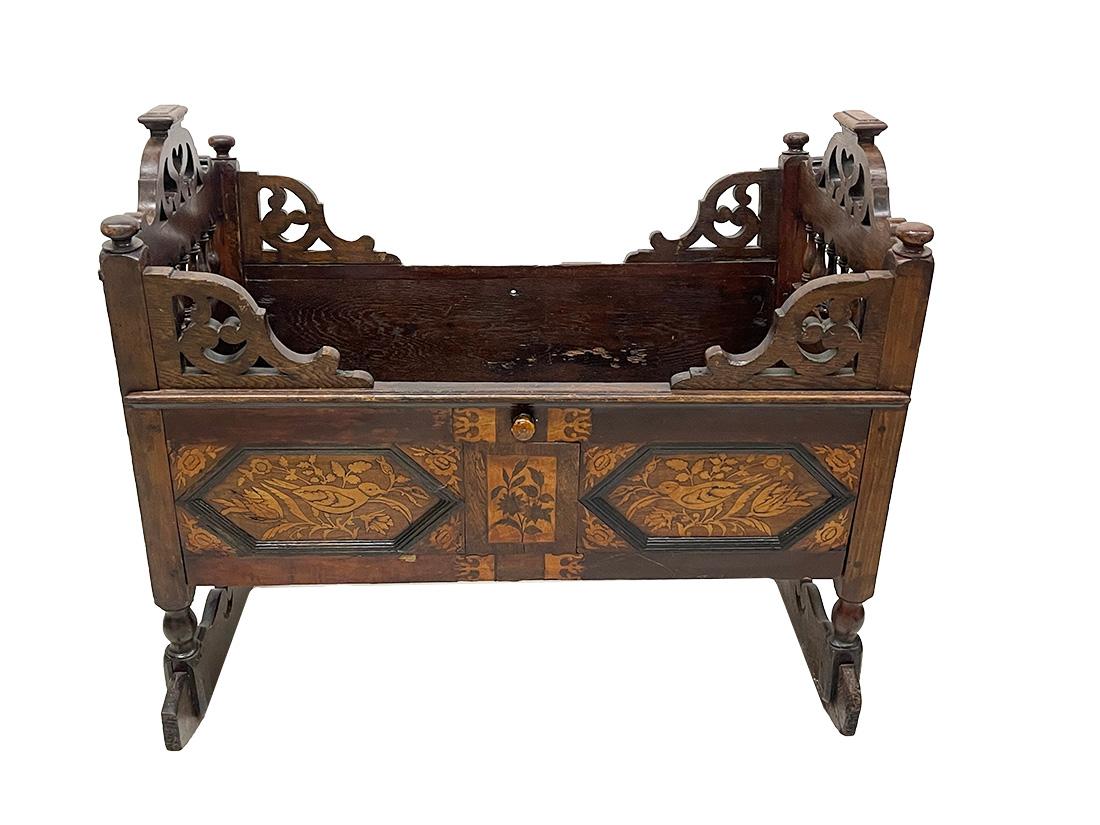 English 18th century oak children's cradle

An 18th century English children's cradle, made of oak, raised on rockers (stands firmly) with marquetry with a scene of flowers and leaves with birds. The sides are mirrored in marquetry in dark and light