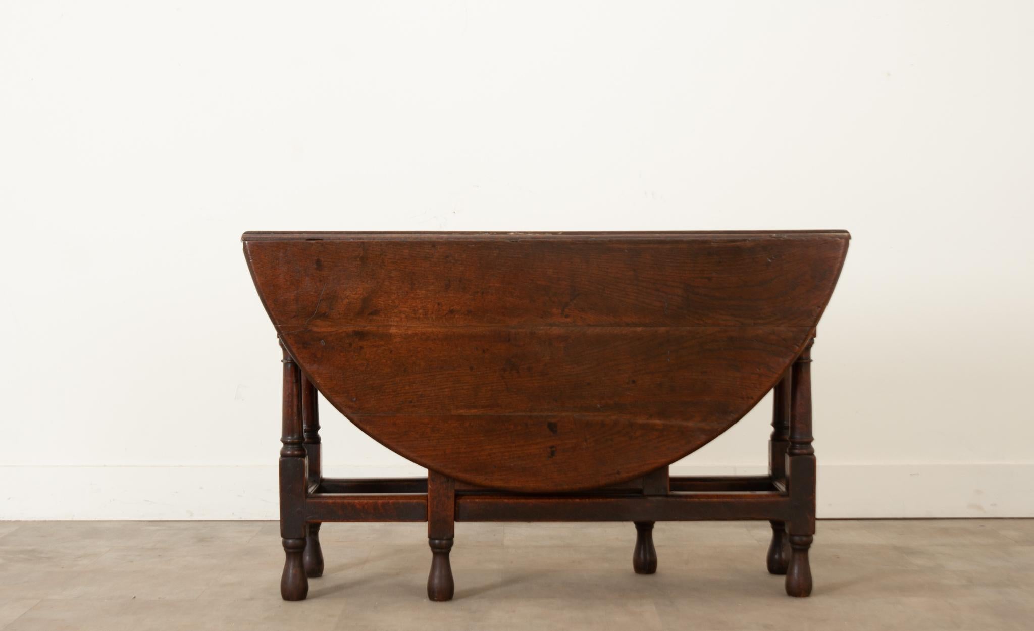 English 18th Century solid oak gateleg table. This table boosts charm and patina only possible with its age and construction. The table is held together with peg joinery and hand cut steel hinges, and has one drawer in the apron on the one side. 