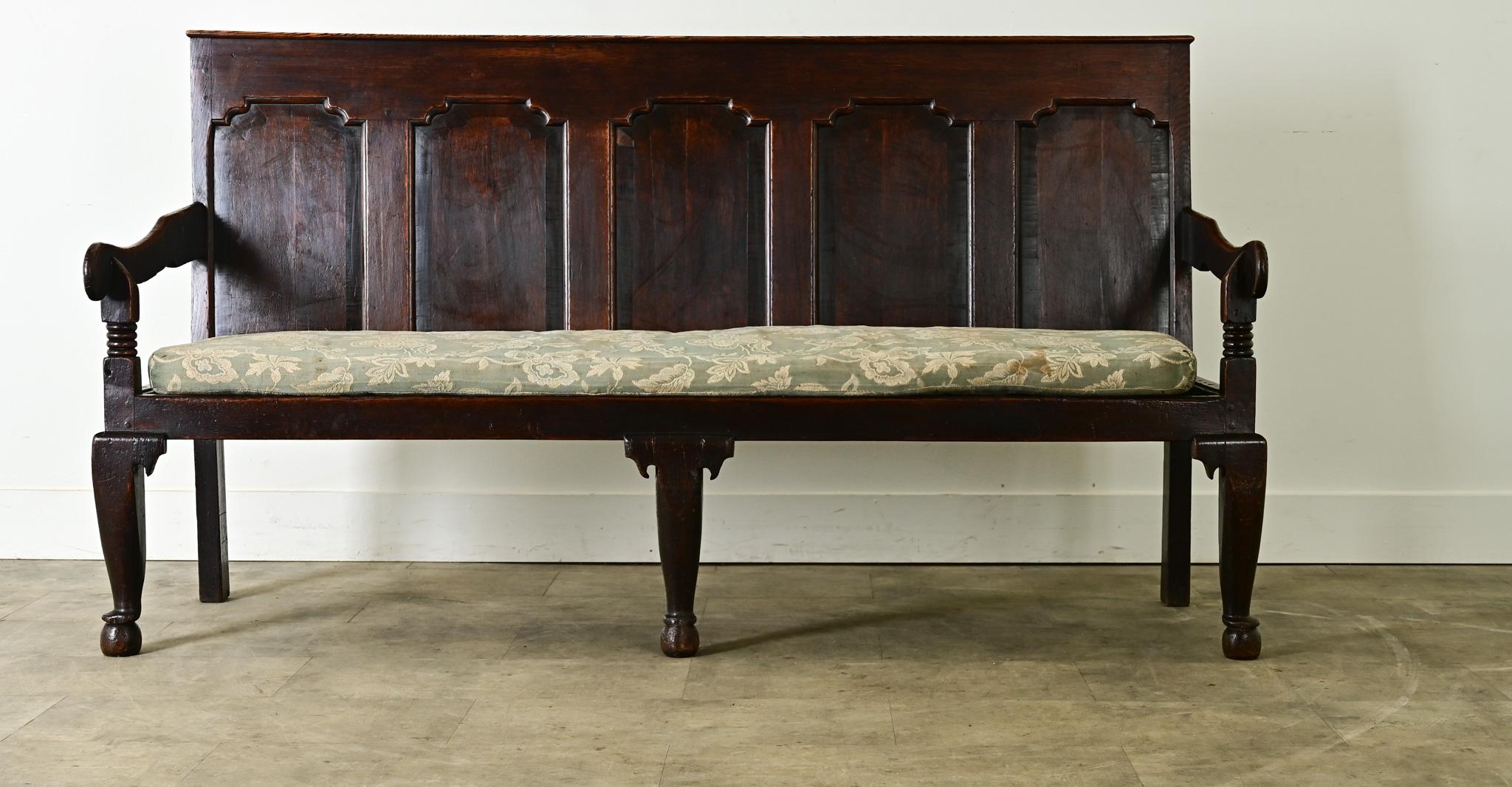Una banqueta o banco inglés de roble de hacia 1780 con majestuosos detalles tallados. Con un respaldo finamente panelado de grandes proporciones -suficientemente largo para sentar cómodamente a tres o cuatro personas-, este encantador asiento está
