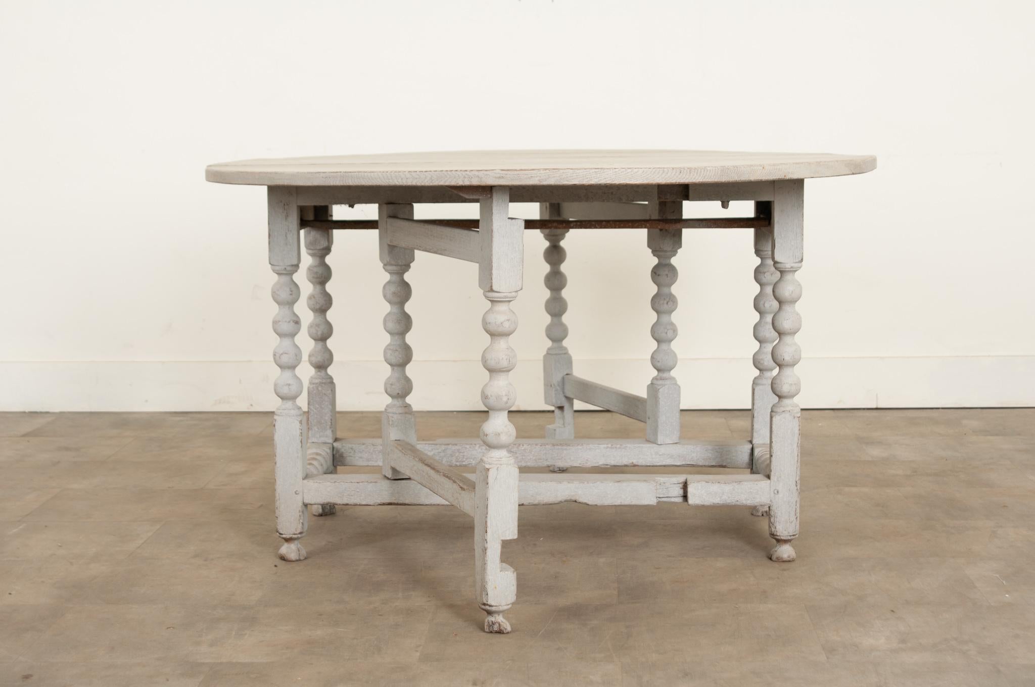 An English oak gateleg table from the 18th century with an oval top and decorative turned legs. An example of a very early gateleg, this table has well proportioned drop leaves and a good folding mechanism. The top rests upon a turned gateleg base
