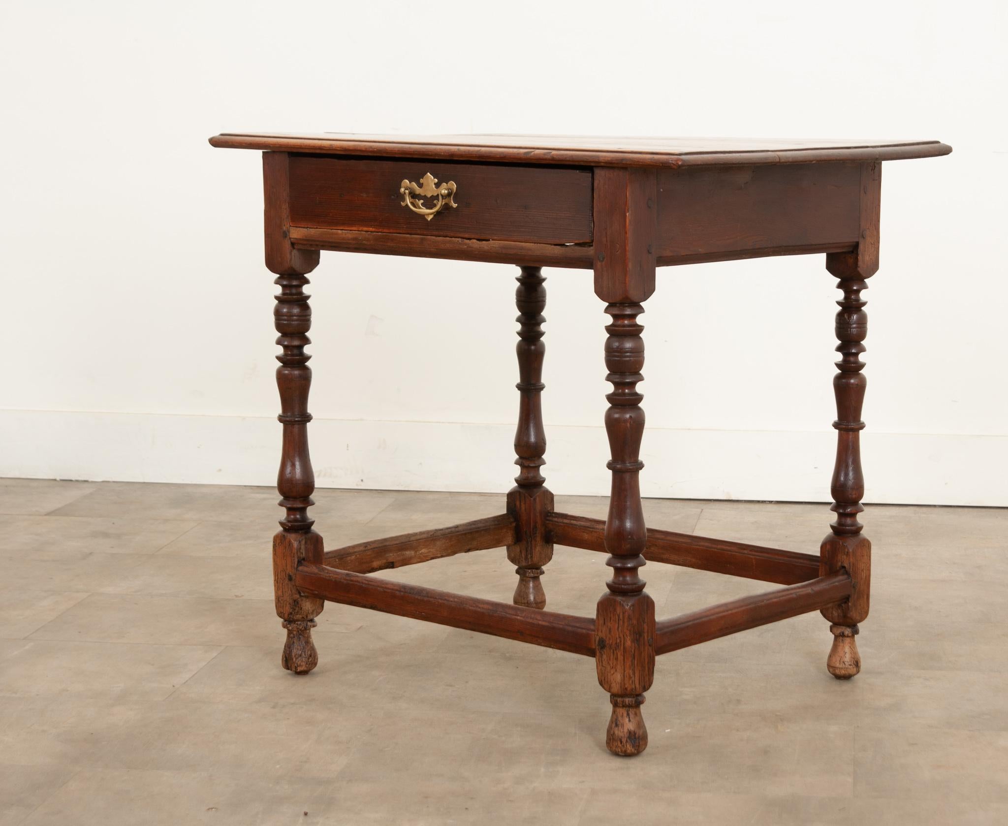 An English side table made from pine in the 1700s. This lovely little table features a rectangular top made using three boards with an ogee edge, nailed and pegged to a simple, straight apron that houses a single drawer in front with a brass winged