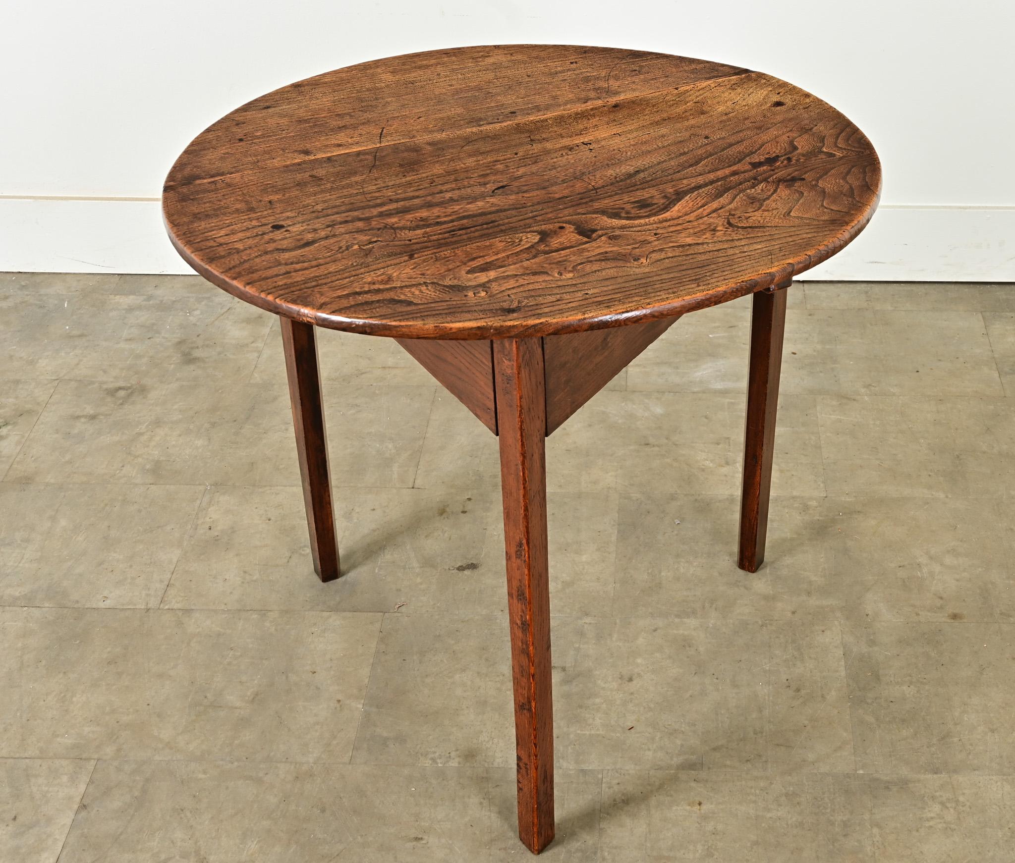 Beautiful, expressive elm was used to construct this wonderful English cricket table. The round top is wonderfully patinated and showcases the extraordinary grain found within. The base is triangular with a deep apron and three linear legs. Used as