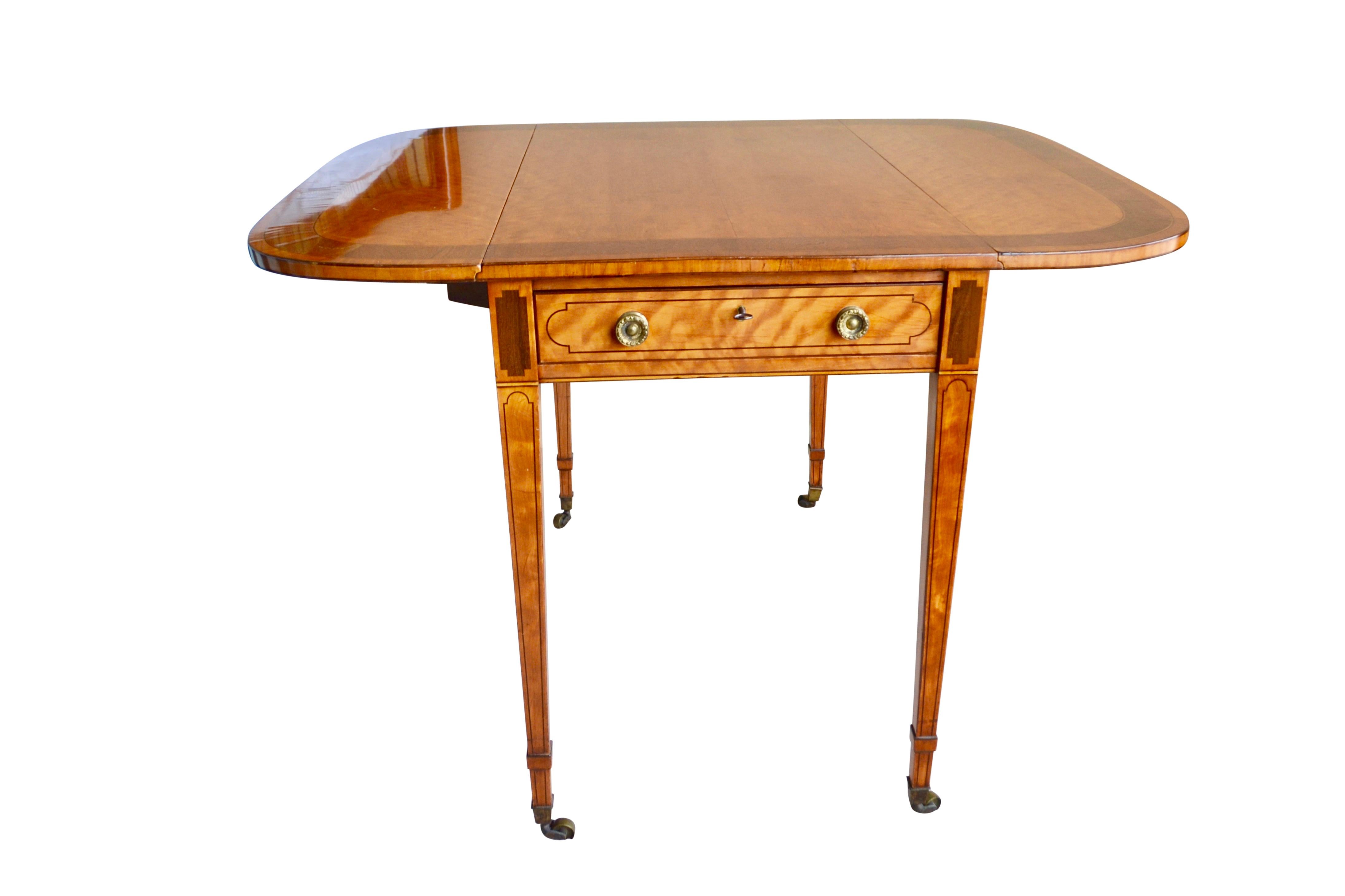 A Classic Georgian English Pembroke table with a single drawer to one side with lock and flaps on either side that can be raised by brackets on hinges (known as “elbows”) to increase its Size. The table is raised on tapered rectangular legs with