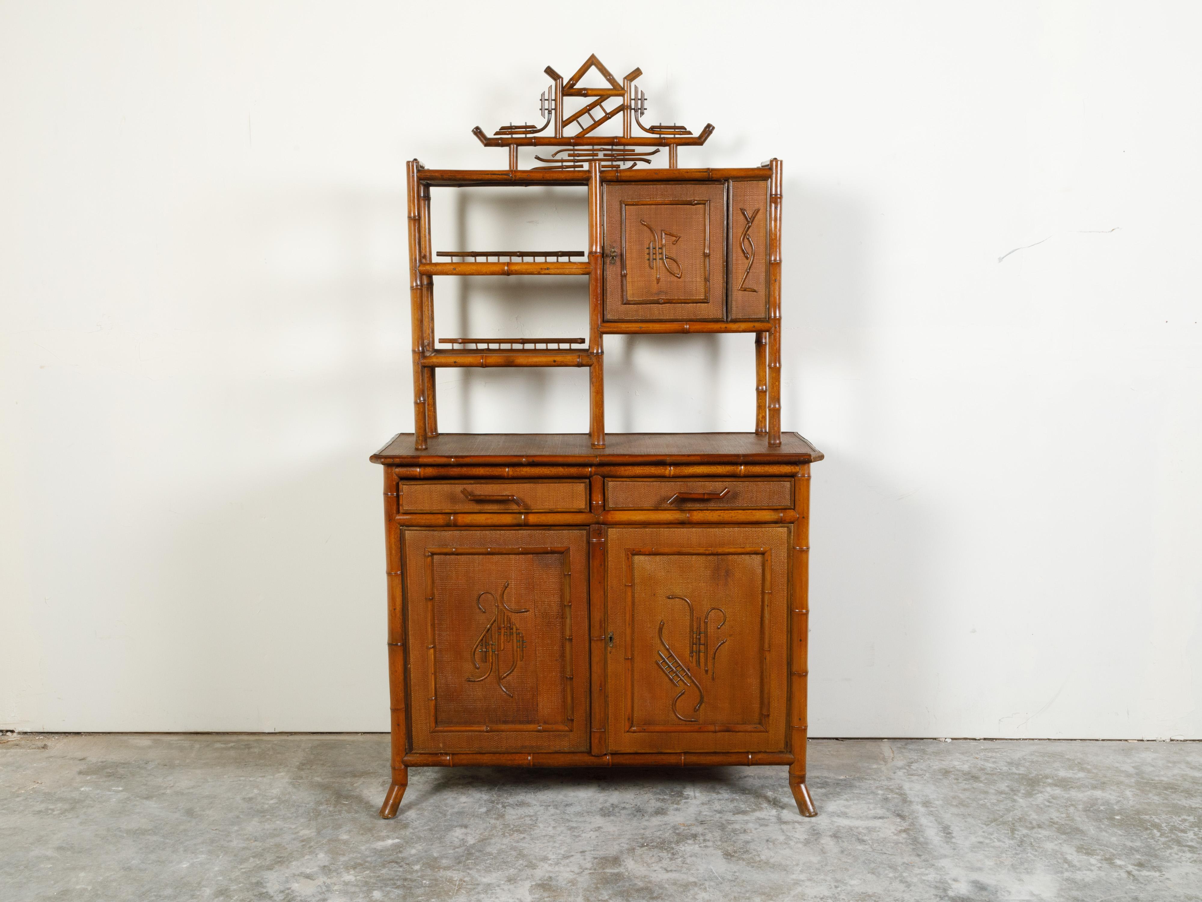 An English bamboo cabinet from the early 20th century, with Chinoiserie motifs, open shelves and lower buffet. Created in England during the early years of the 20th century, this bamboo cabinet features open shelves and a single door in the upper