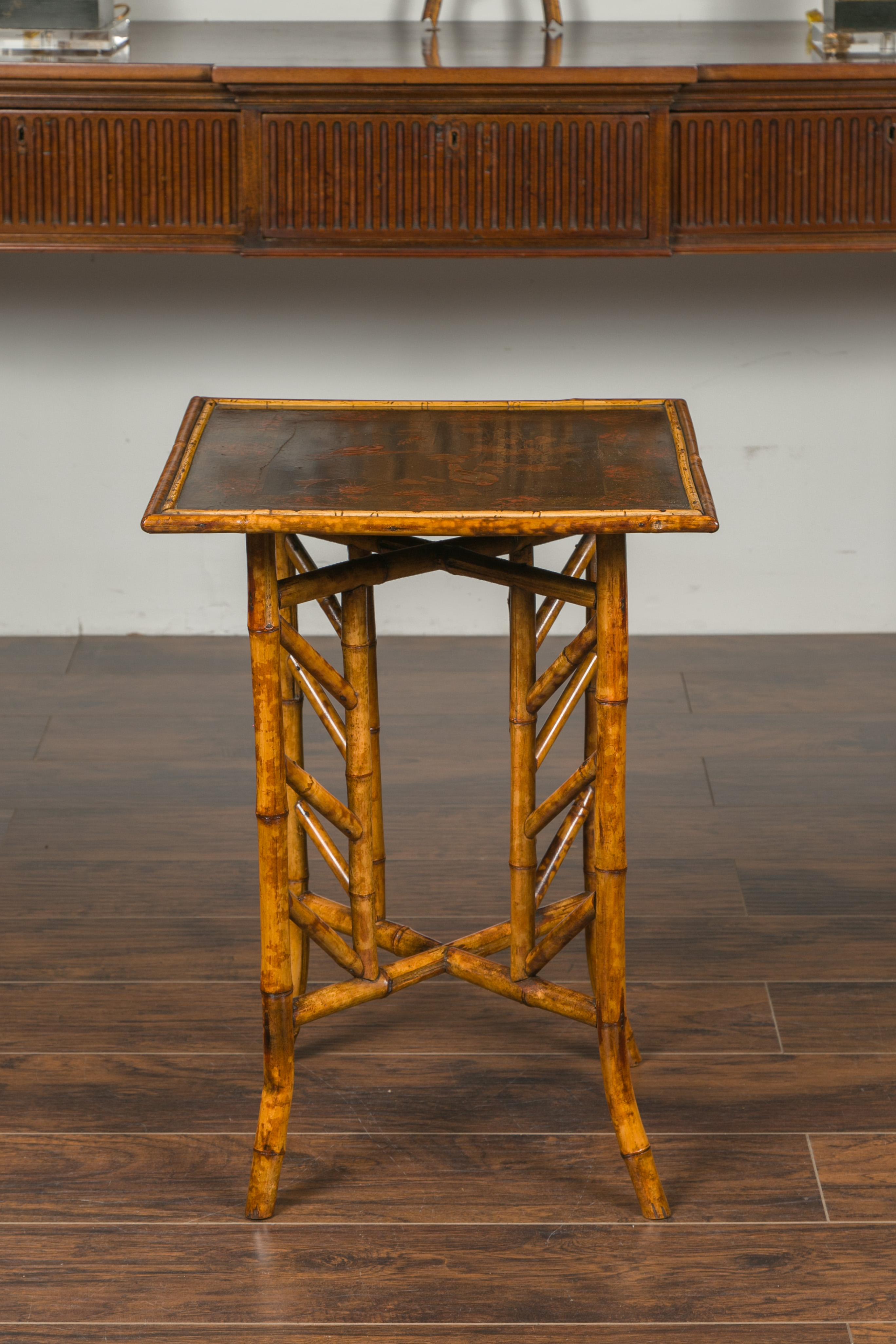 An English bamboo side table from the early 20th century, with bird and floral decor. Created in England during the turn of the century, this bamboo side table features a square top adorned with two birds, one of them perched on a plant while the