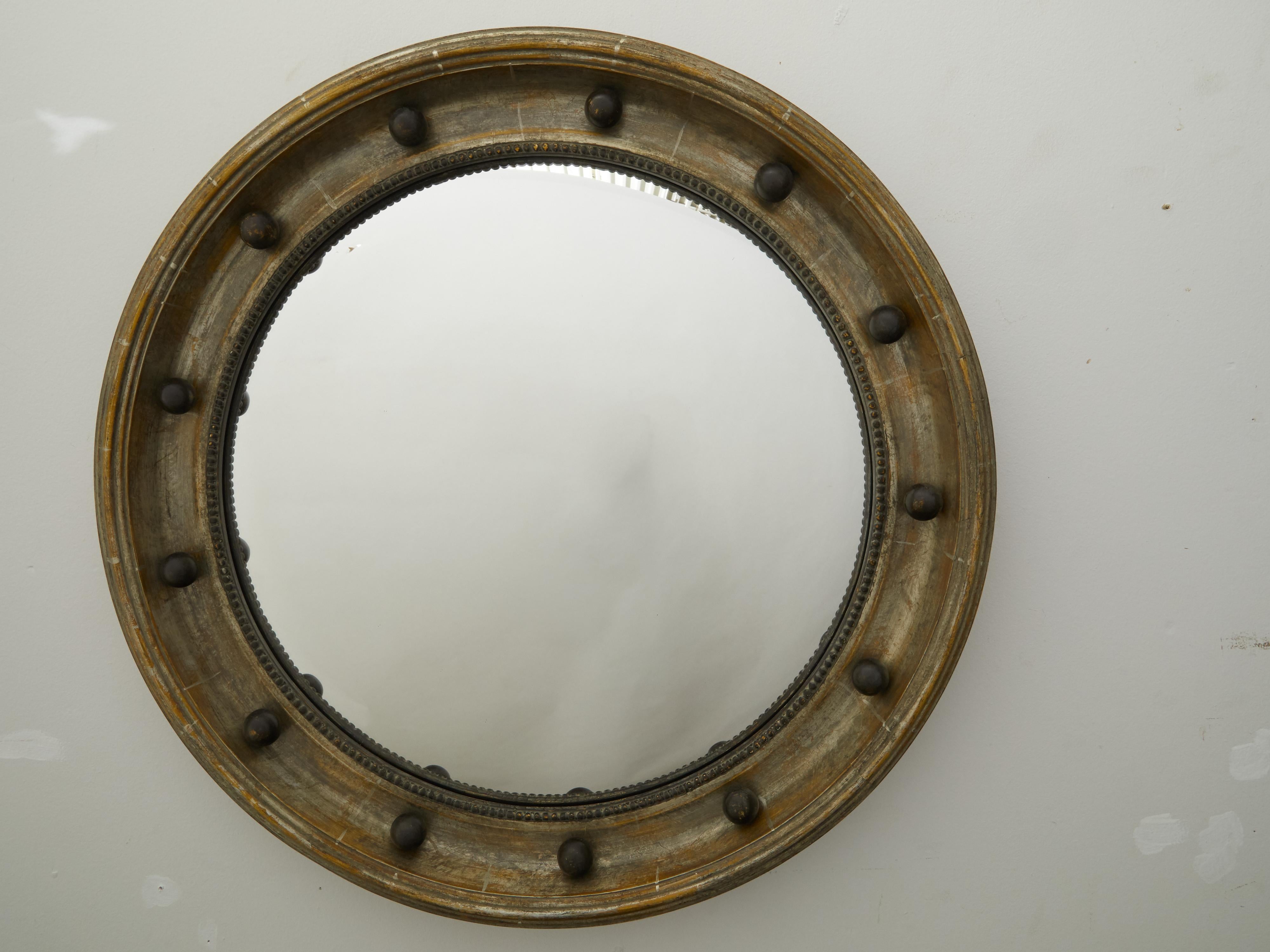 Miroir convexe en forme d'œil de bœuf du début du 20e siècle, avec des accents ébénisés et des motifs perlés. Créé en Angleterre au début du XXe siècle, ce miroir girandole à feuilles d'argent présente un cadre circulaire rehaussé de petites sphères