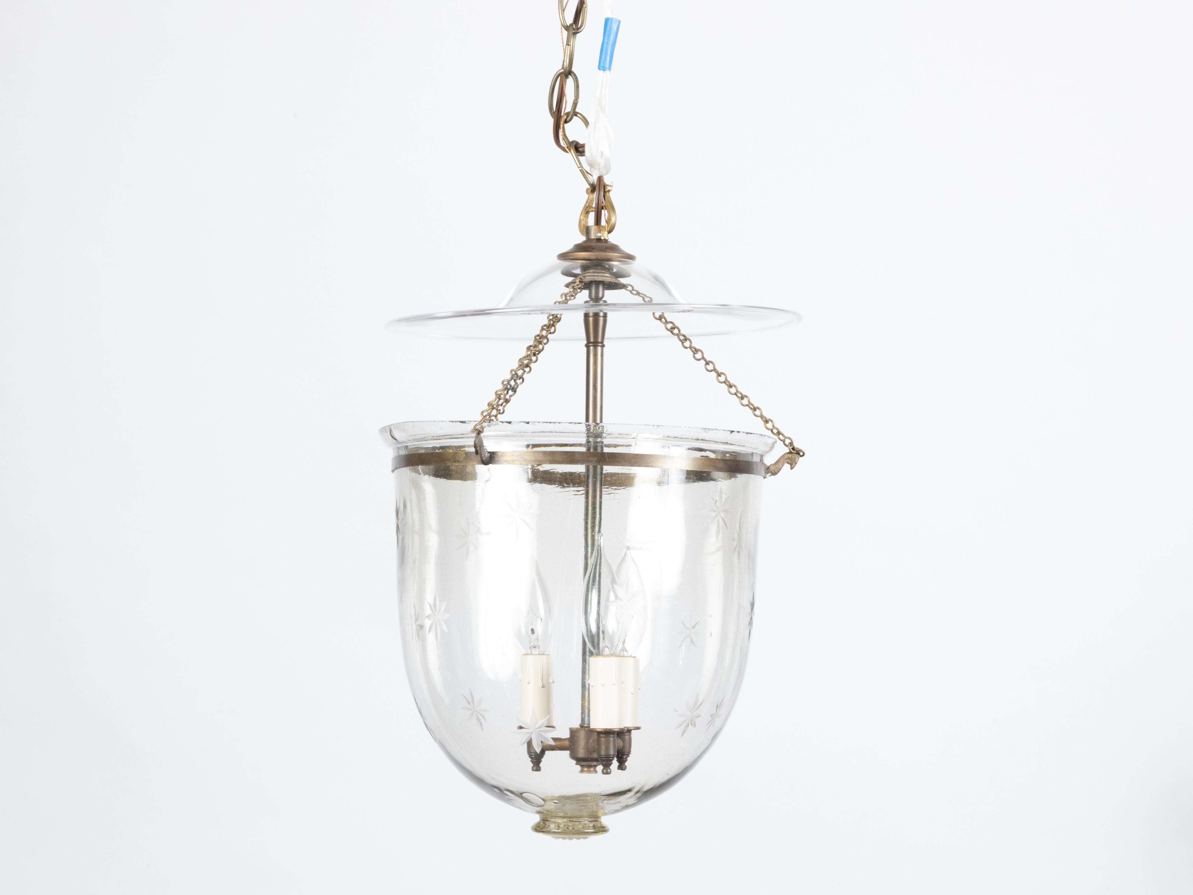 Un luminaire anglais en forme de cloche du début du 20e siècle, avec trois lumières et des étoiles gravées. Créé en Angleterre au tournant du siècle, ce luminaire en forme de cloche présente un corps en verre orné de discrets motifs étoilés gravés,