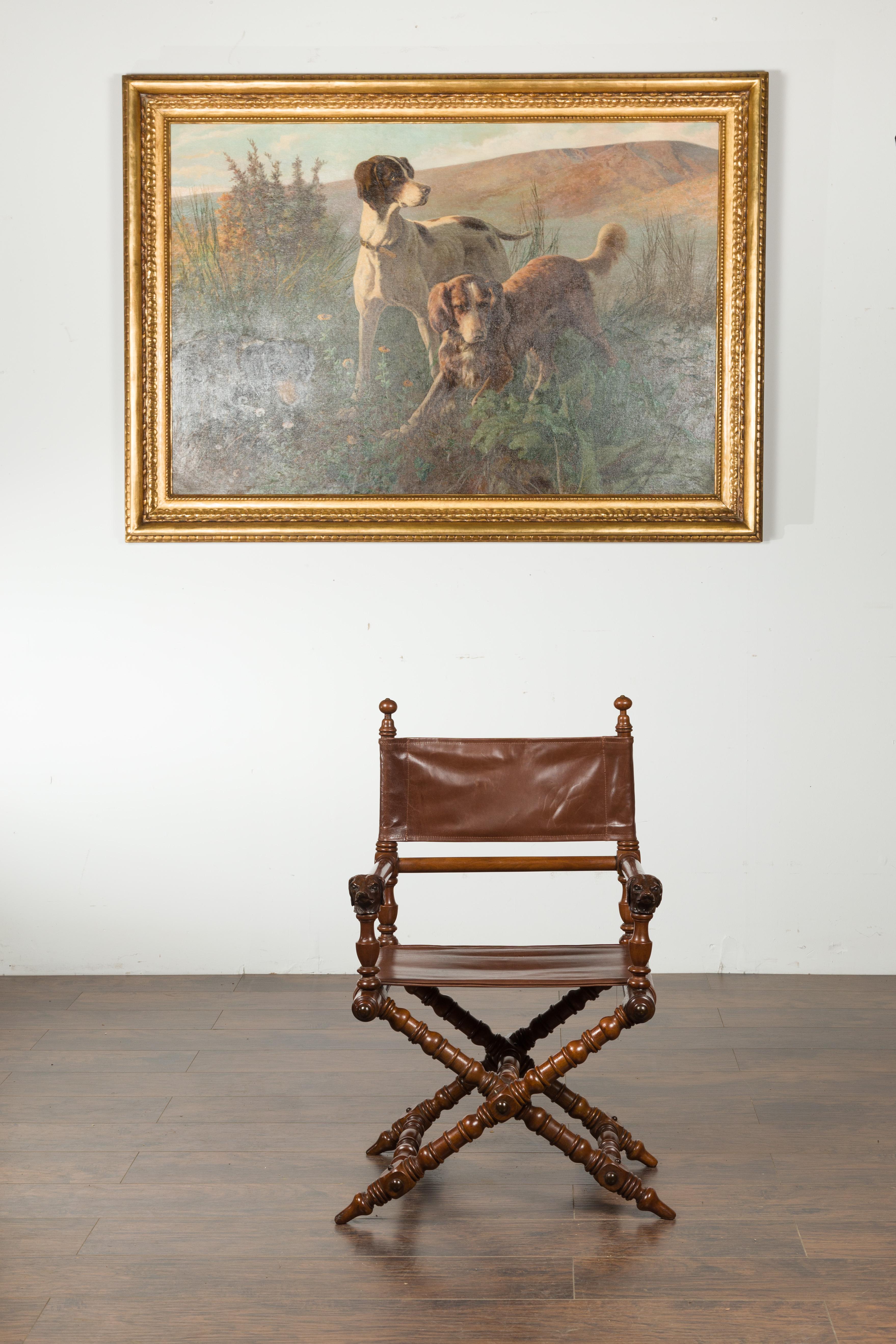 An English walnut chair from the turn of the century, with carved dog heads, leather seat and turned base. Created in England in the early years of the 20th century, this wooden chair features a leather seat and back, resting on an elegant turned