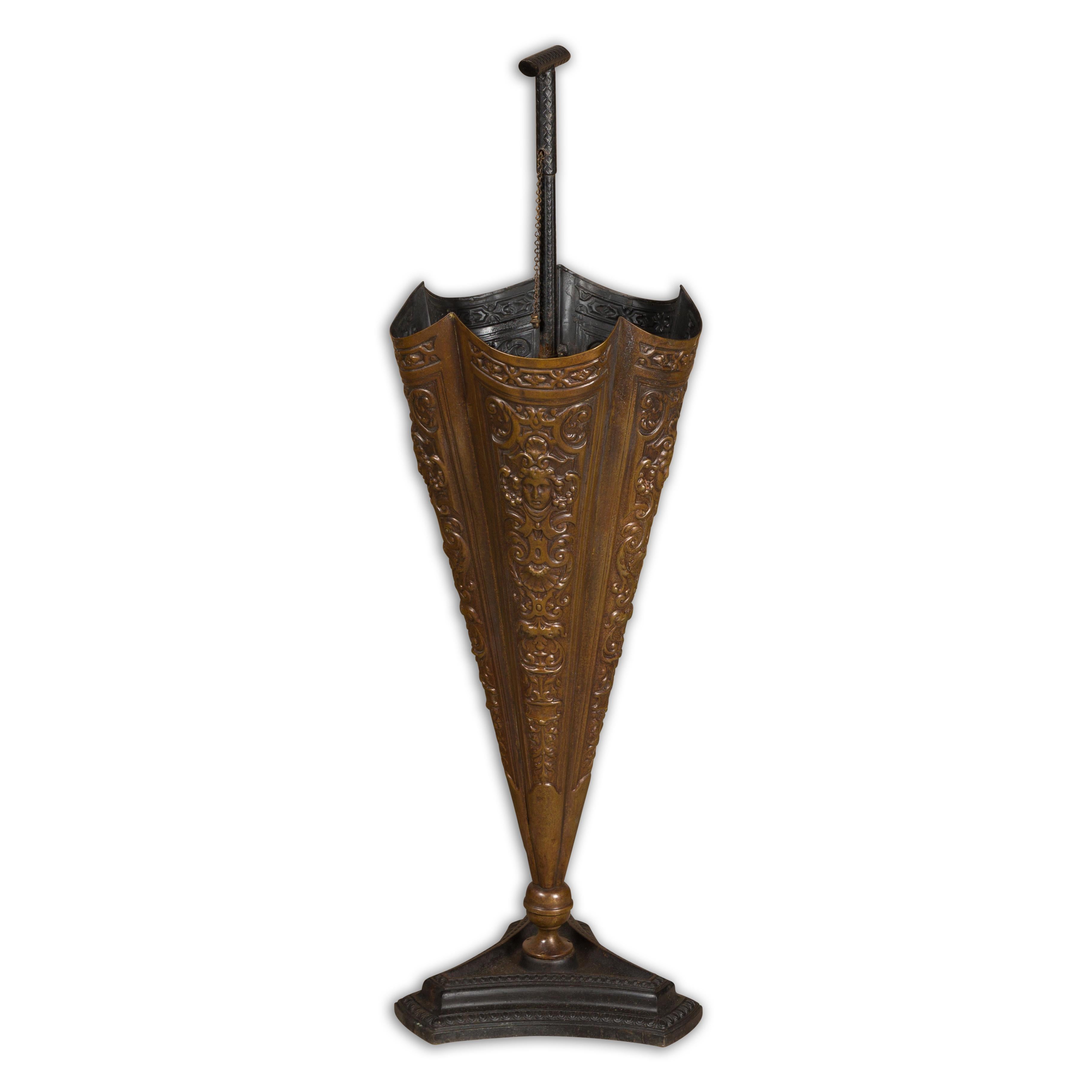 An English brass umbrella stand from circa 1920-1930 shaped as an umbrella with raised motifs and tripartite base. Step into the world of whimsical charm with this English brass umbrella stand from the vibrant era of the 1920s-1930s. Artfully