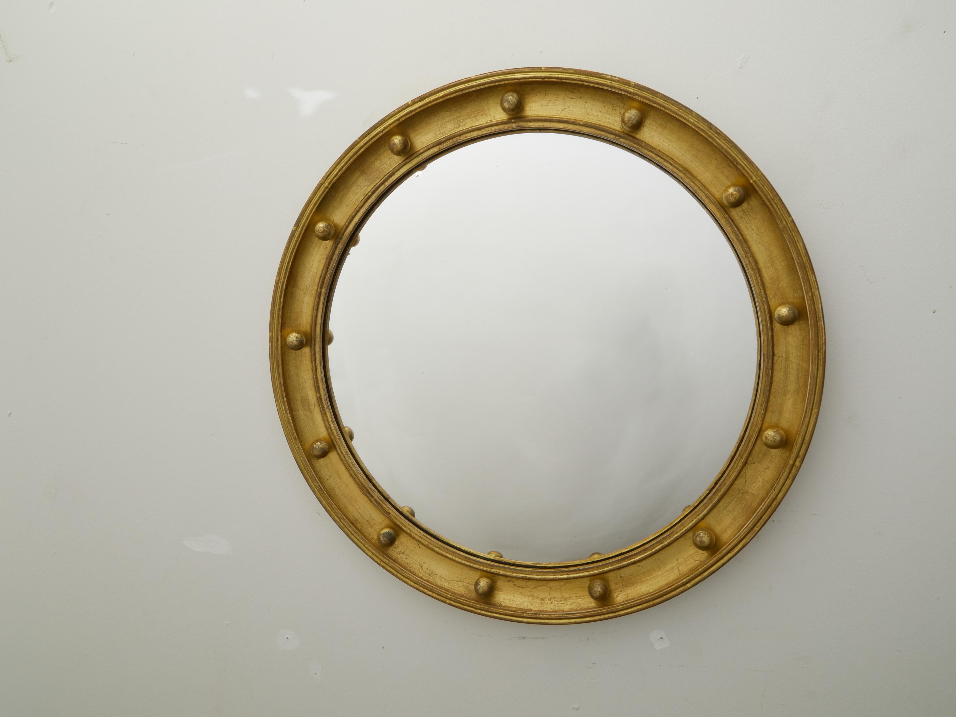 An English giltwood bullseye convex girandole mirror from the early 20th century, with petite spheres. Created in England during the second quarter of the 20th century, this circular mirror features a convex mirror plate surrounded by a gilded frame