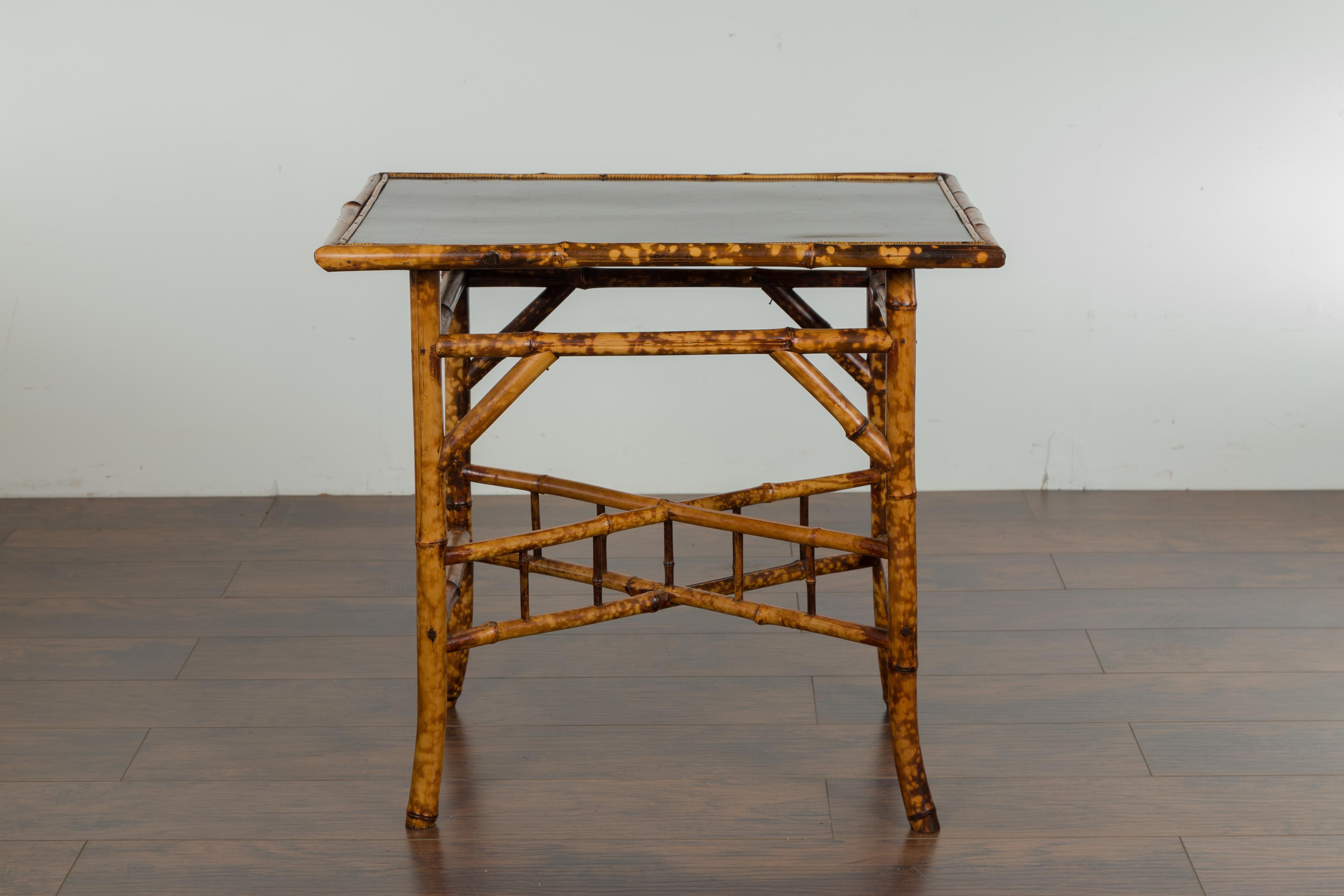 An English bamboo side table from the early 20th century, with ebonized top. Created in England during the first quarter of the 20th century, this side table features a rectangular ebonized top with geometric motifs, sitting above a bamboo base made