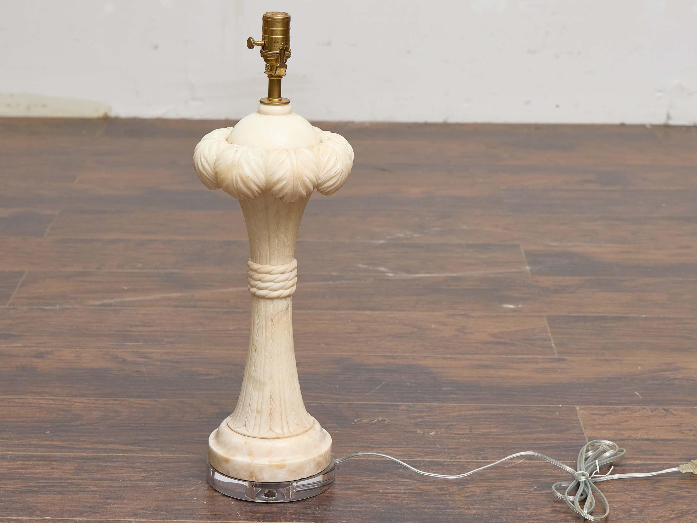 An English carved marble table lamp dating to circa 1920, newly wired for use in the USA and mounted on a custom clear lucite base. The lamp’s carved column tapers upward from a circular foot, encircled at midsection with a rope motif, and