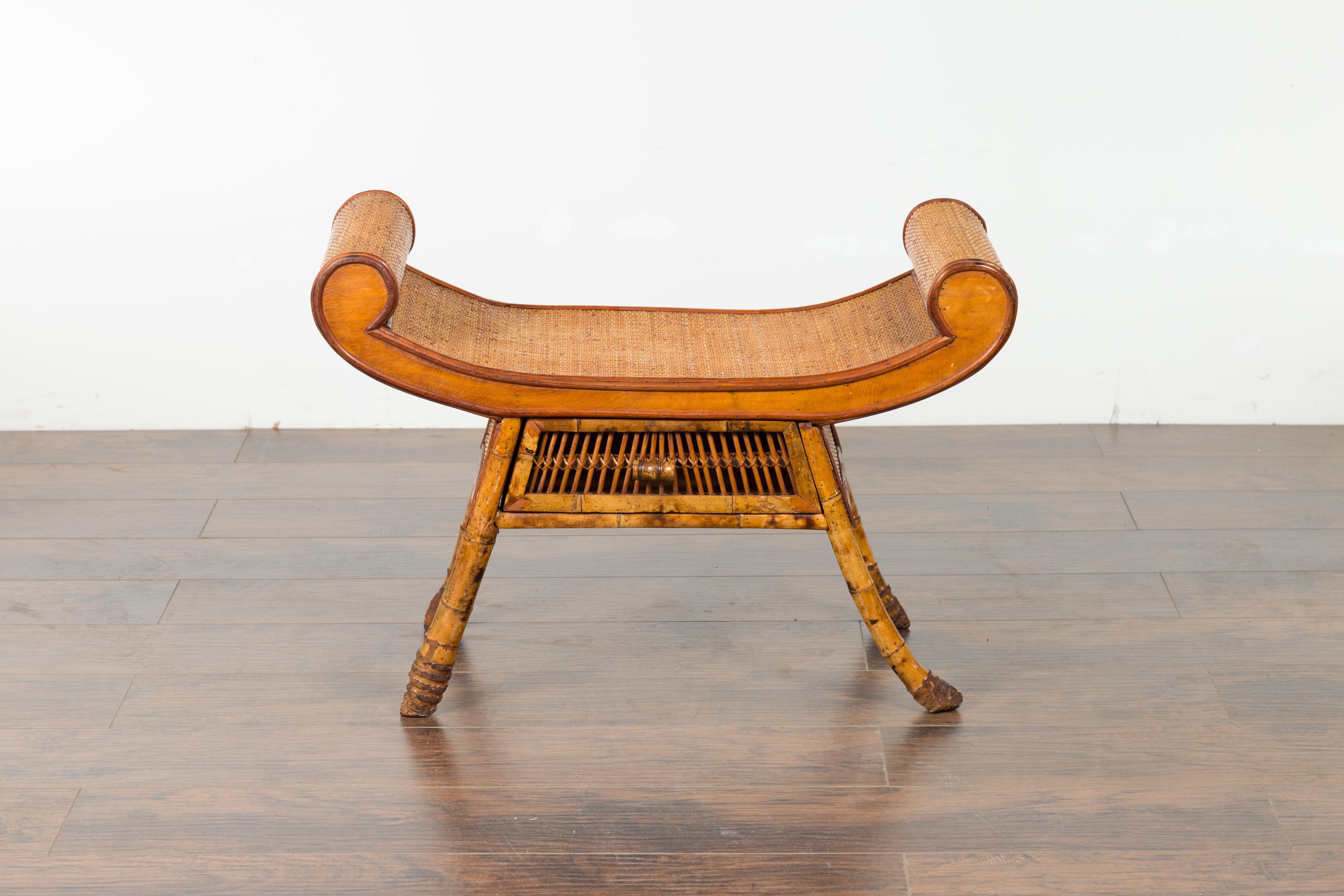 An English bamboo and rattan bench from the early 20th century, with scrolling extremities and single drawer. Created in England during the first quarter of the 20th century, this small bench charms us with its Chinese inspiration and natural