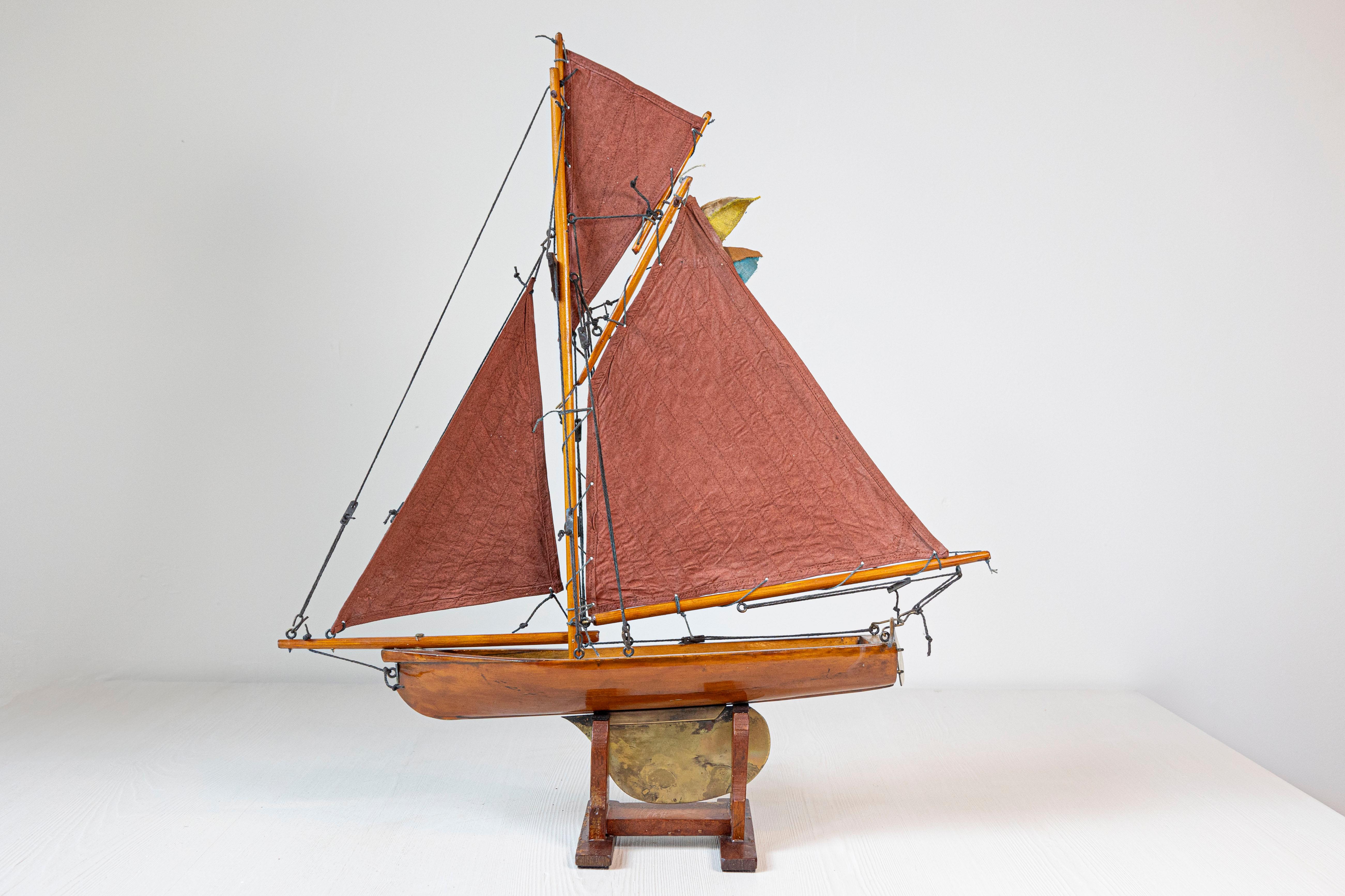 Yate estanque Gaff Cutter inglés de época Jorge V de hacia 1920 con velas rojas sobre base personalizada. Este elegante yate estanque Gaff Cutter inglés de la época de Jorge V, de hacia 1920, es una sorprendente mezcla de historia náutica y