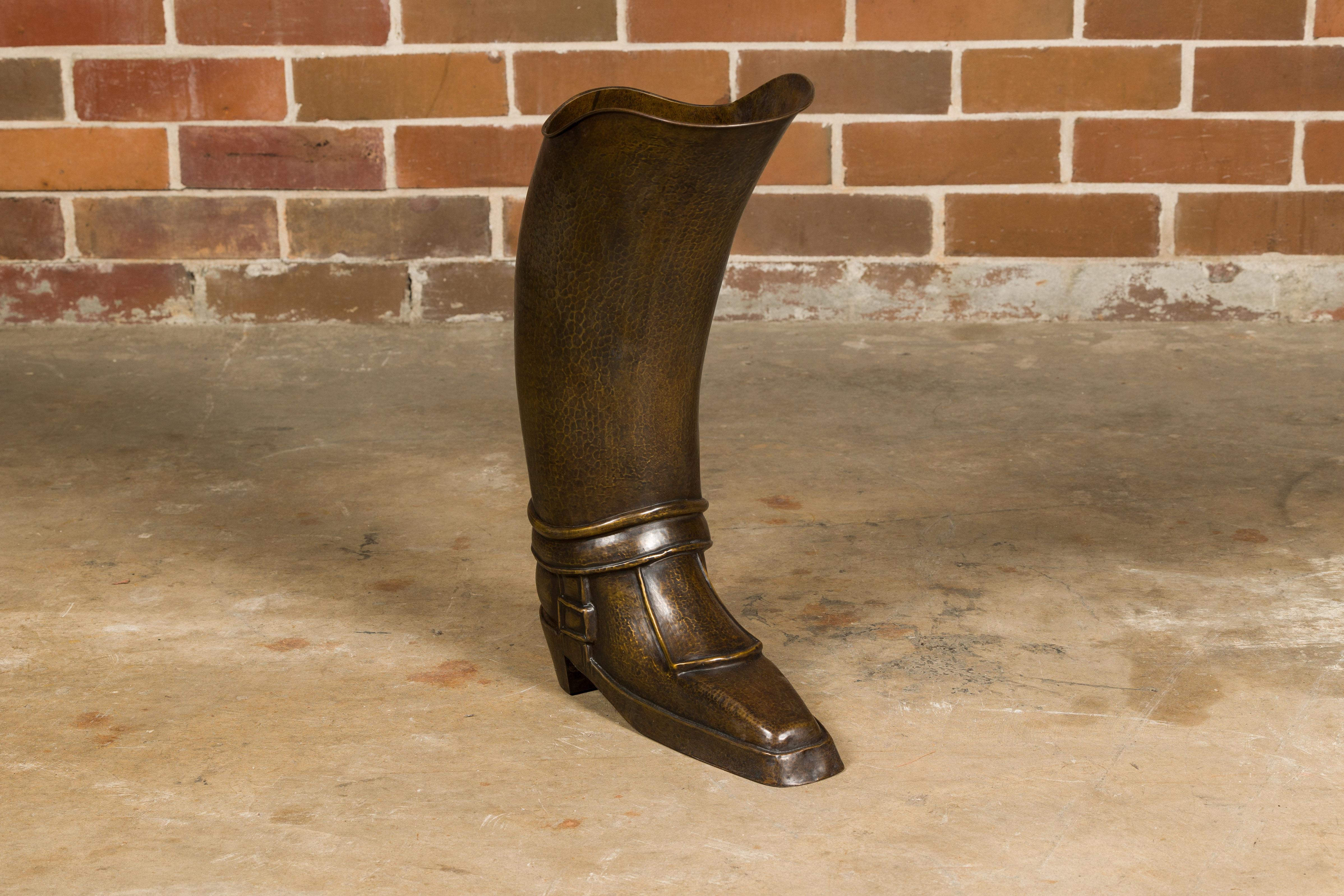 An English hand-hammered brass and copper musketeer boot umbrella stand from circa 1920 with front buckle. Step into a world of antique charm with this English hand-hammered brass and copper musketeer boot umbrella stand from circa 1920, a piece
