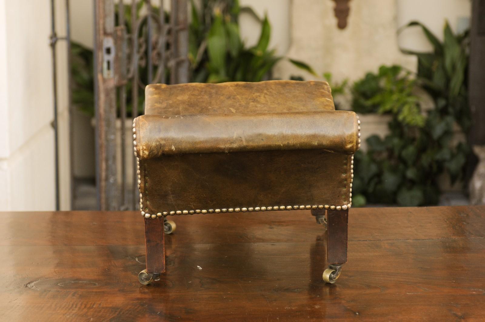 20th Century English 1920s Leather Gout Stool with Out-Scrolling Back, Nailheads and Casters