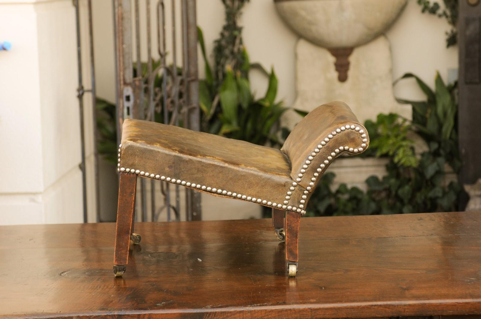 English 1920s Leather Gout Stool with Out-Scrolling Back, Nailheads and Casters 1