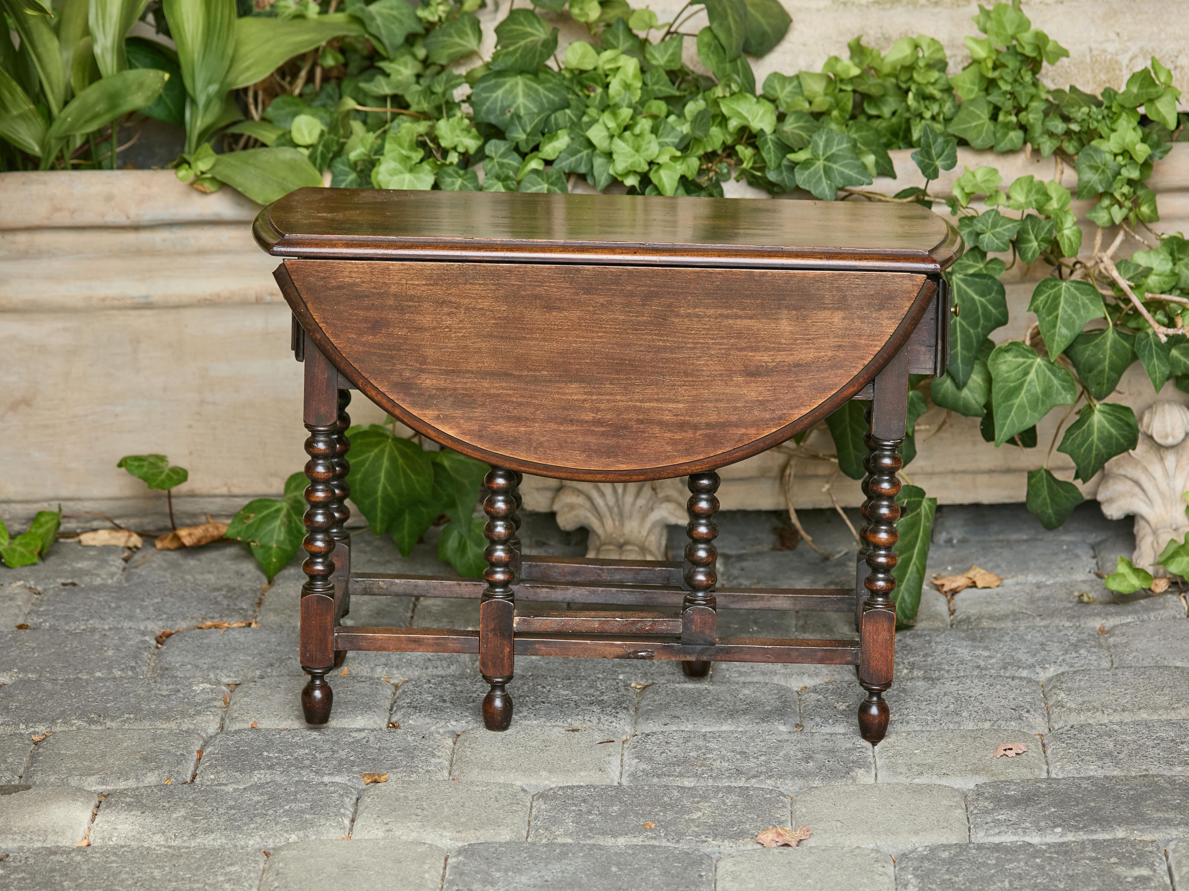 Table à abattant en chêne anglais, datant de 1920 environ, avec des pieds en forme de bobine et des tiroirs latéraux. Cette table à abattant en chêne anglais datant d'environ 1920 est une pièce charmante et fonctionnelle qui allie praticité et