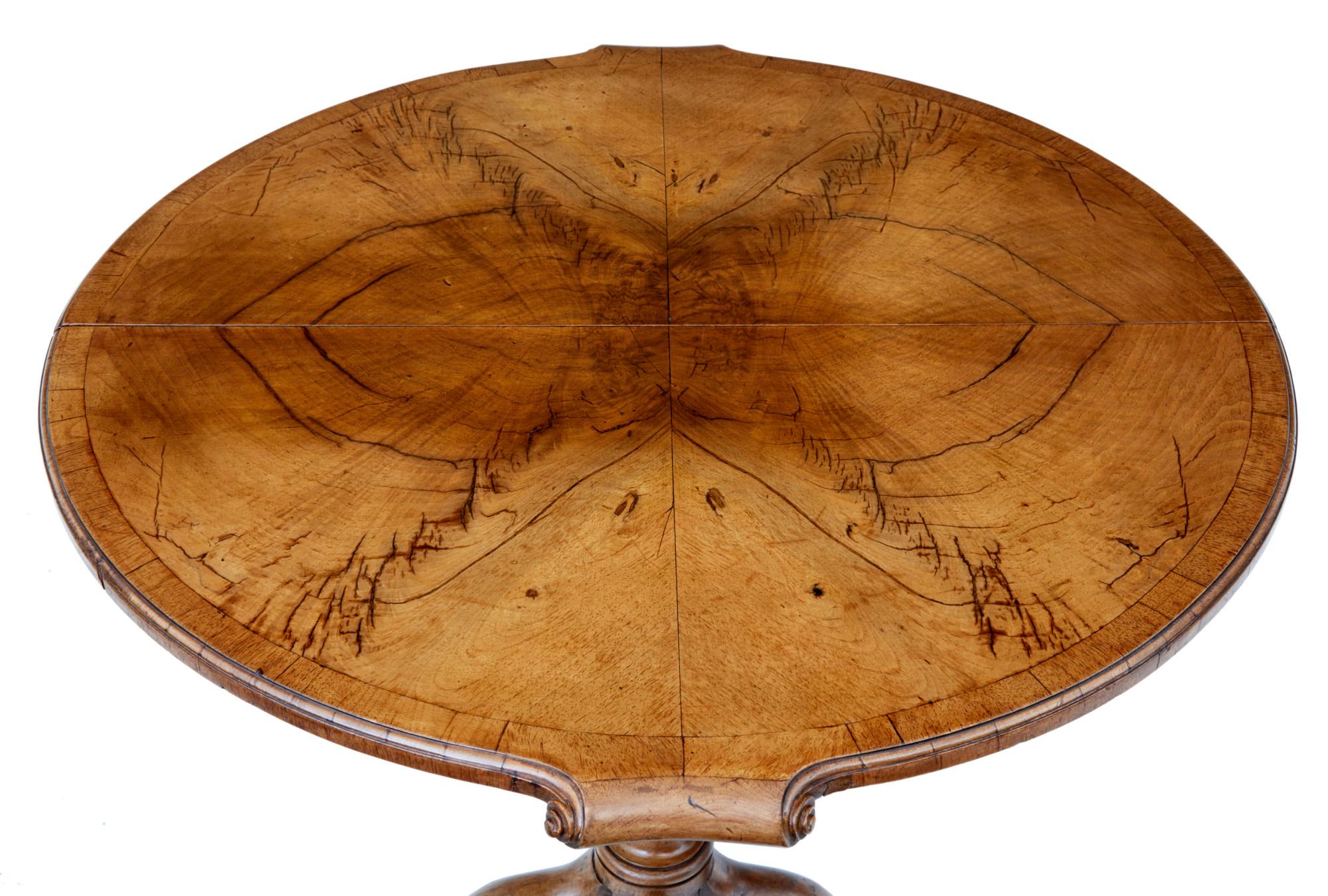 A small English walnut occasional extension table circa 1920 with butterfly veneer top, out-scrolling effects, one removable leaf, turned pedestal base and four curving legs. Add a touch of timeless elegance to your space with this English
