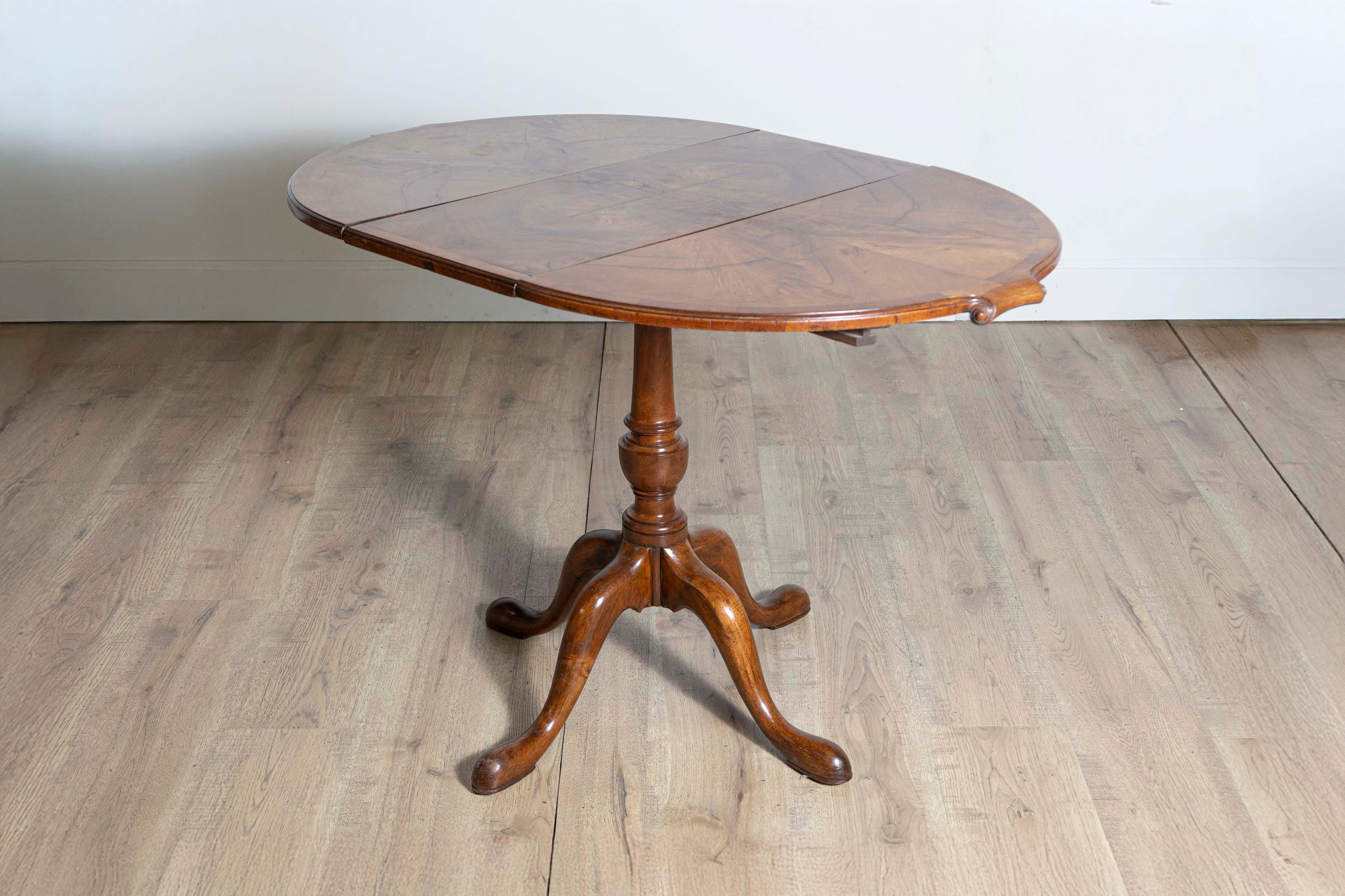 A small English walnut occasional extension table circa 1920 with butterfly veneer top, out-scrolling effects, one removable leaf, turned pedestal base and four curving legs. Add a touch of timeless elegance to your space with this English