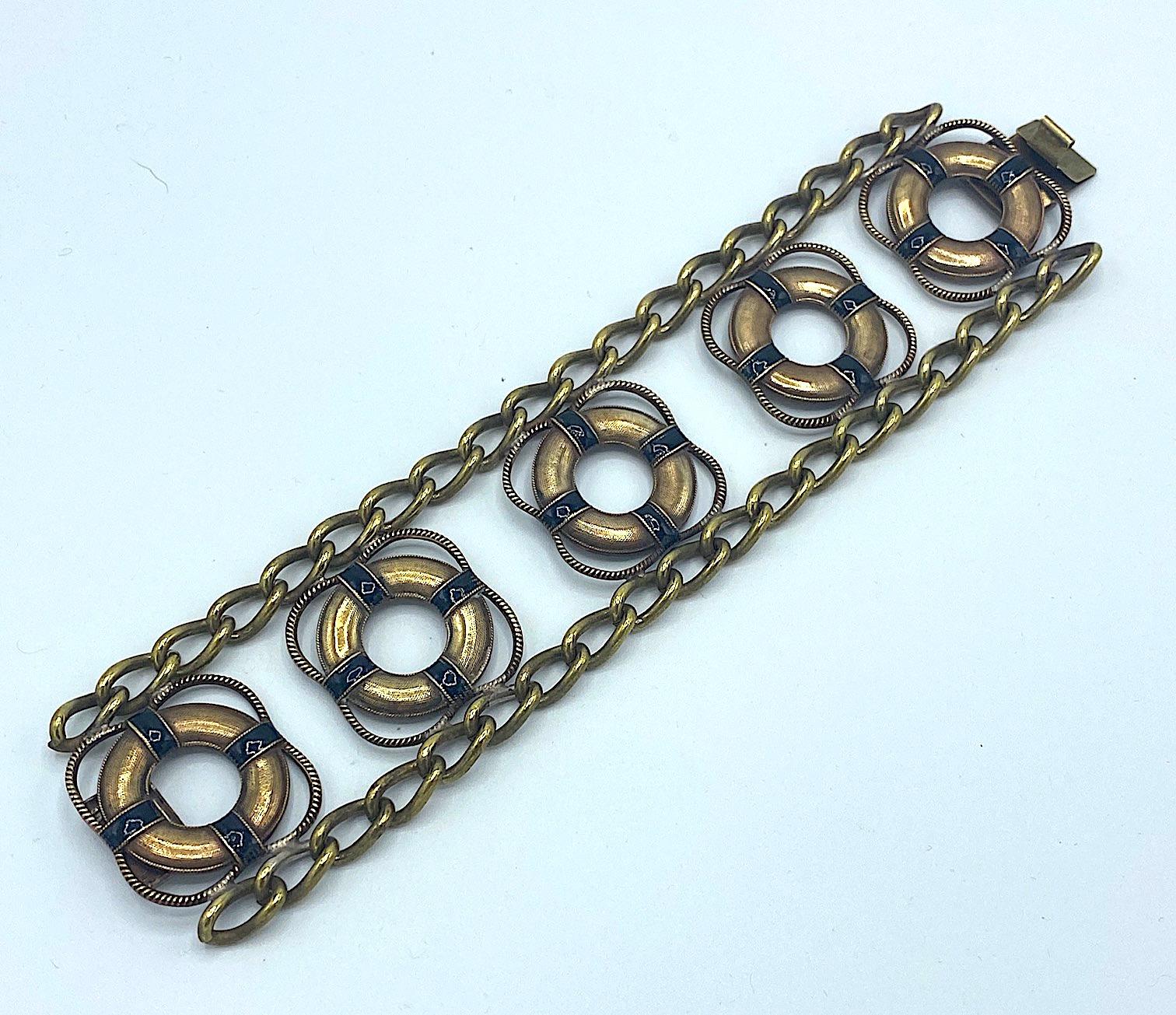 Un très inhabituel et rare bracelet anglais sur le thème de la navigation de plaisance en plaqué or sur laiton avec émail noir et datant de la fin des années 1930 au début des années 1940. Le bracelet est grand et mesure 1,75 pouce de large et 8