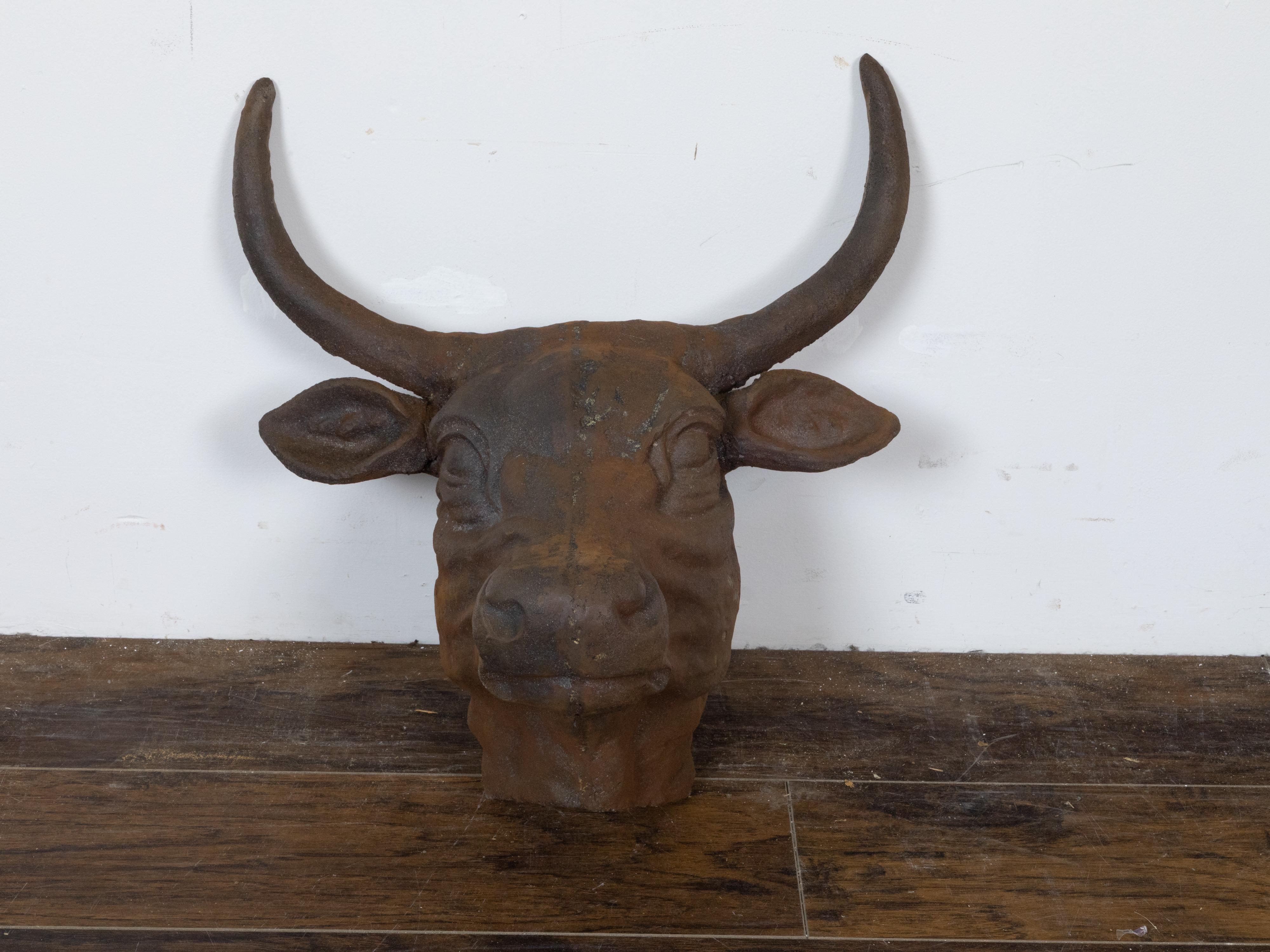 This English cast iron bull wall hanging sculpture, dating back to circa 1930-1940, presenting large antlers and a rustic, rusty patina. The sculpture embodies the essence of English artistry from this period, combining bold design and skilled