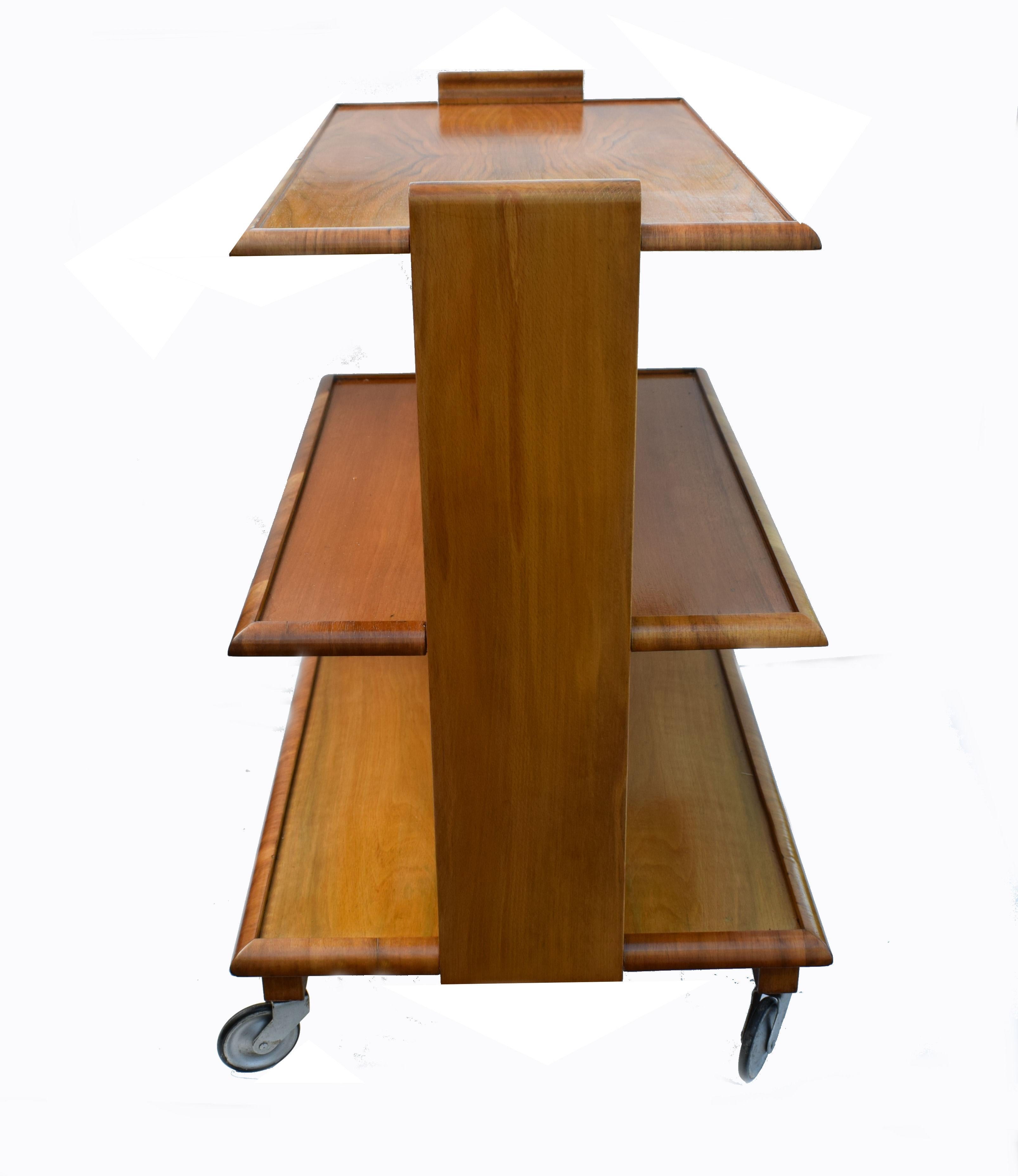 Fabulous 1930s Art Deco walnut three-tier hostess trolley cart in quality vintage solid veneered wood. Three tiers that graduate in with giving lots of generous sized shelving space. Great size for modern use and the everything works perfectly.