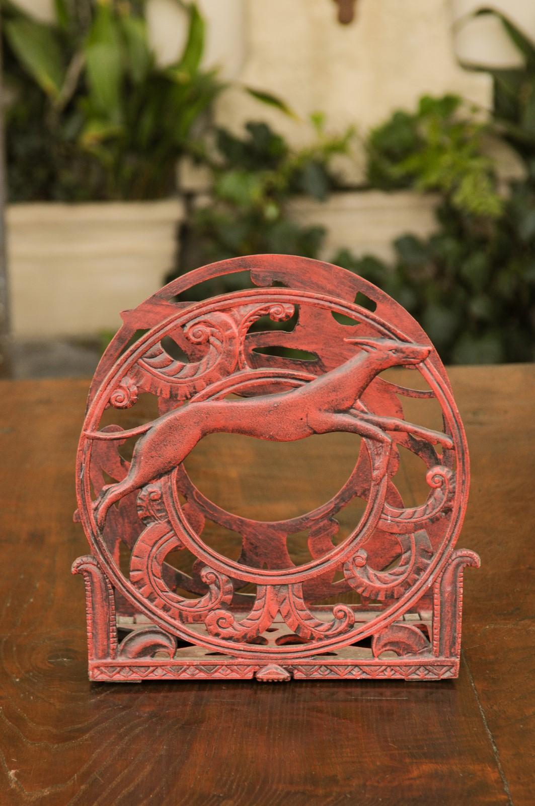 An English red painted metal magazine rack from the first half of the 20th century, with greyhound or whippet dogs in medallions. Born in England during the 1930s, this exquisite circular magazine rack features medallions on each of its sides, each