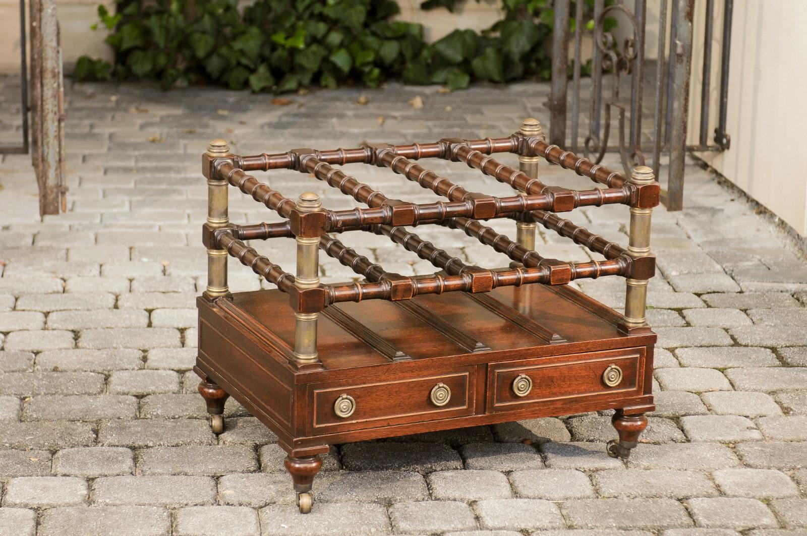 An English mahogany magazine rack on casters from the mid-20th century, with faux bamboo accents, two drawers and brass details. Born in England during the second quarter of the 20th century, this handsome magazine rack features brass details and