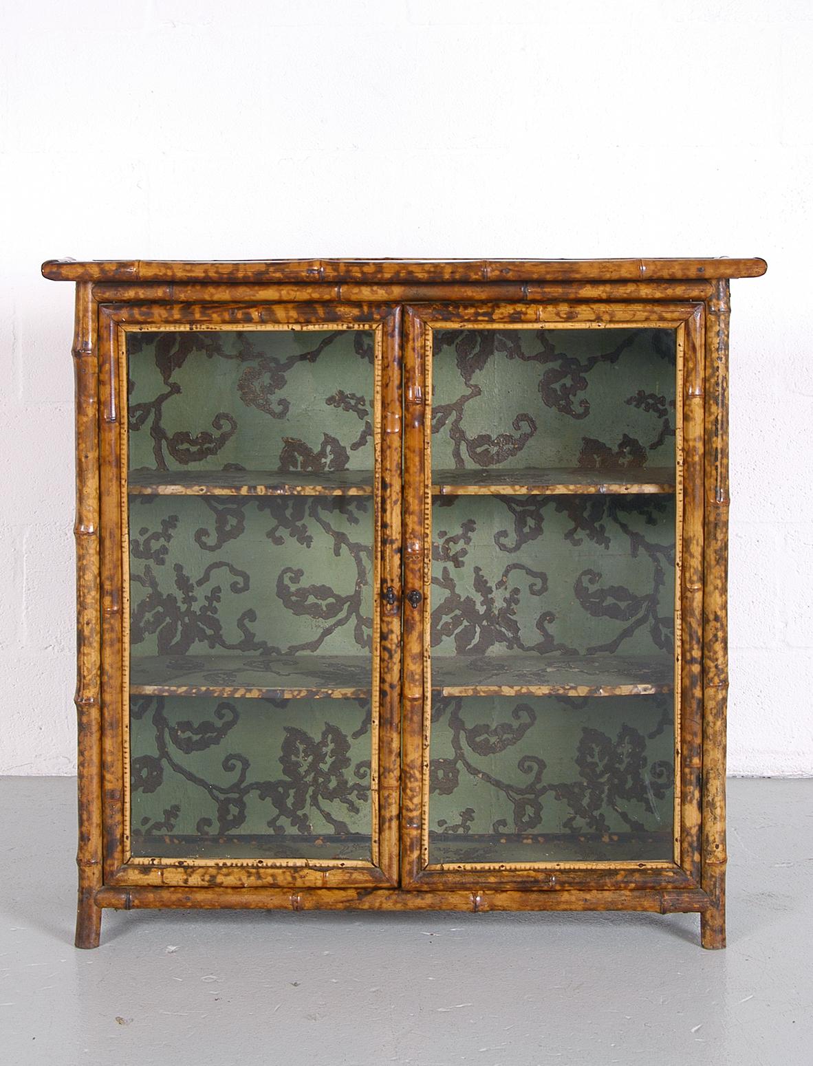 This late 19th century Anglo-Japanese Tortoishell bamboo glass fronted two-door cabinet / bookshelf with original Japanning and lacquered top is a wonderful English antique, which has a beautiful look about it. Complete with original ‘wobbly’ glass