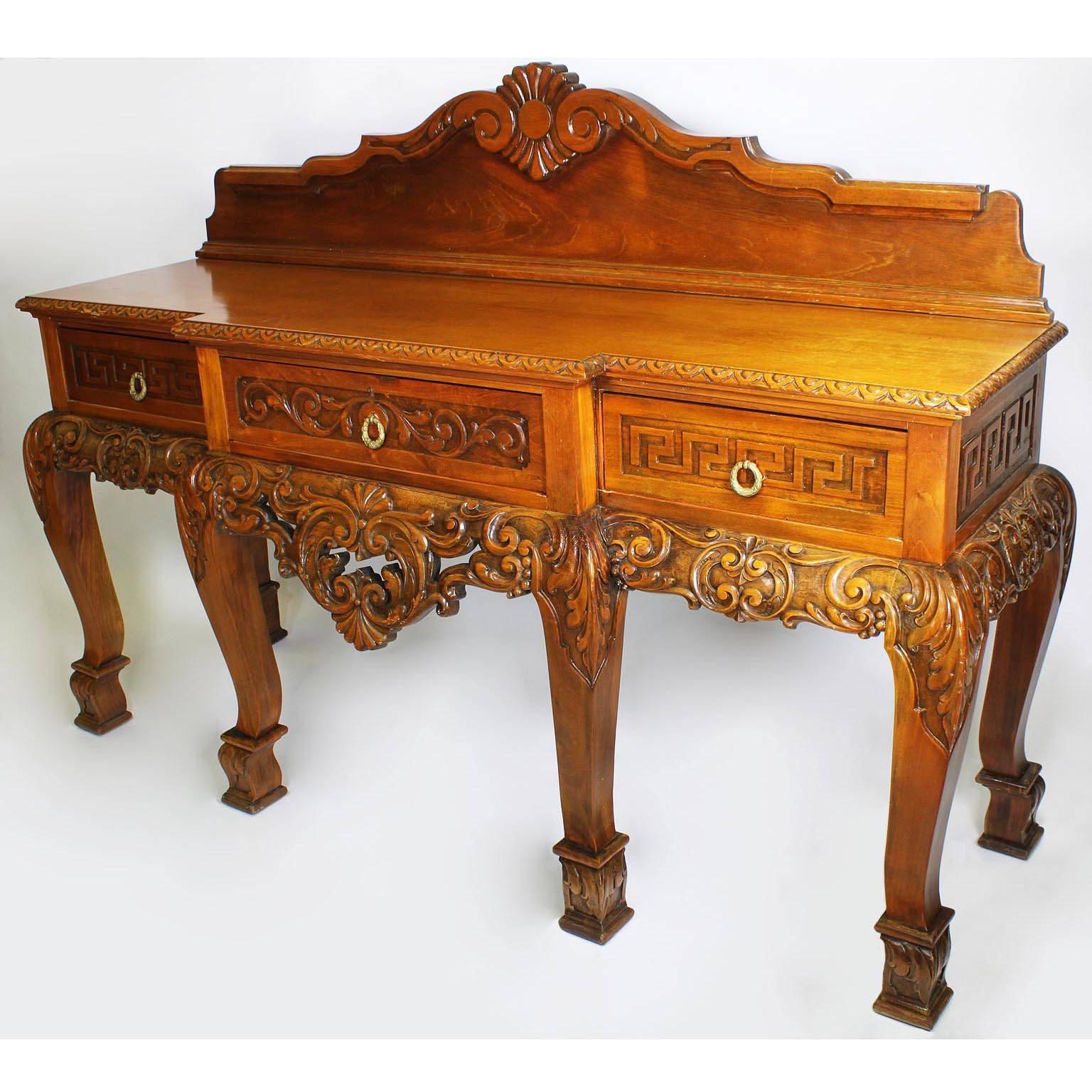 A large English 19th-20th century Chippendale style carved light-walnut three-drawer console - server buffet. The rectangular shaped body surmounted with a carved back molding, the floral carved three-drawer apron, the side drawers with a