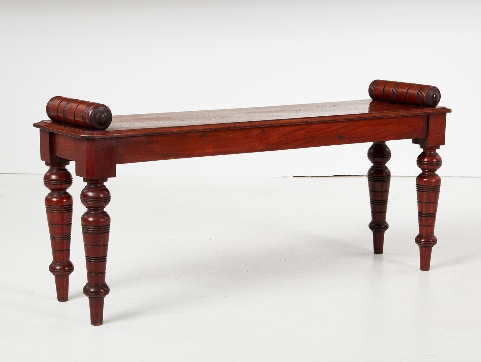A mahogany hall bench with bolster ends above solid seat and turned, ringed legs, having very good color. William IV, circa 1835.