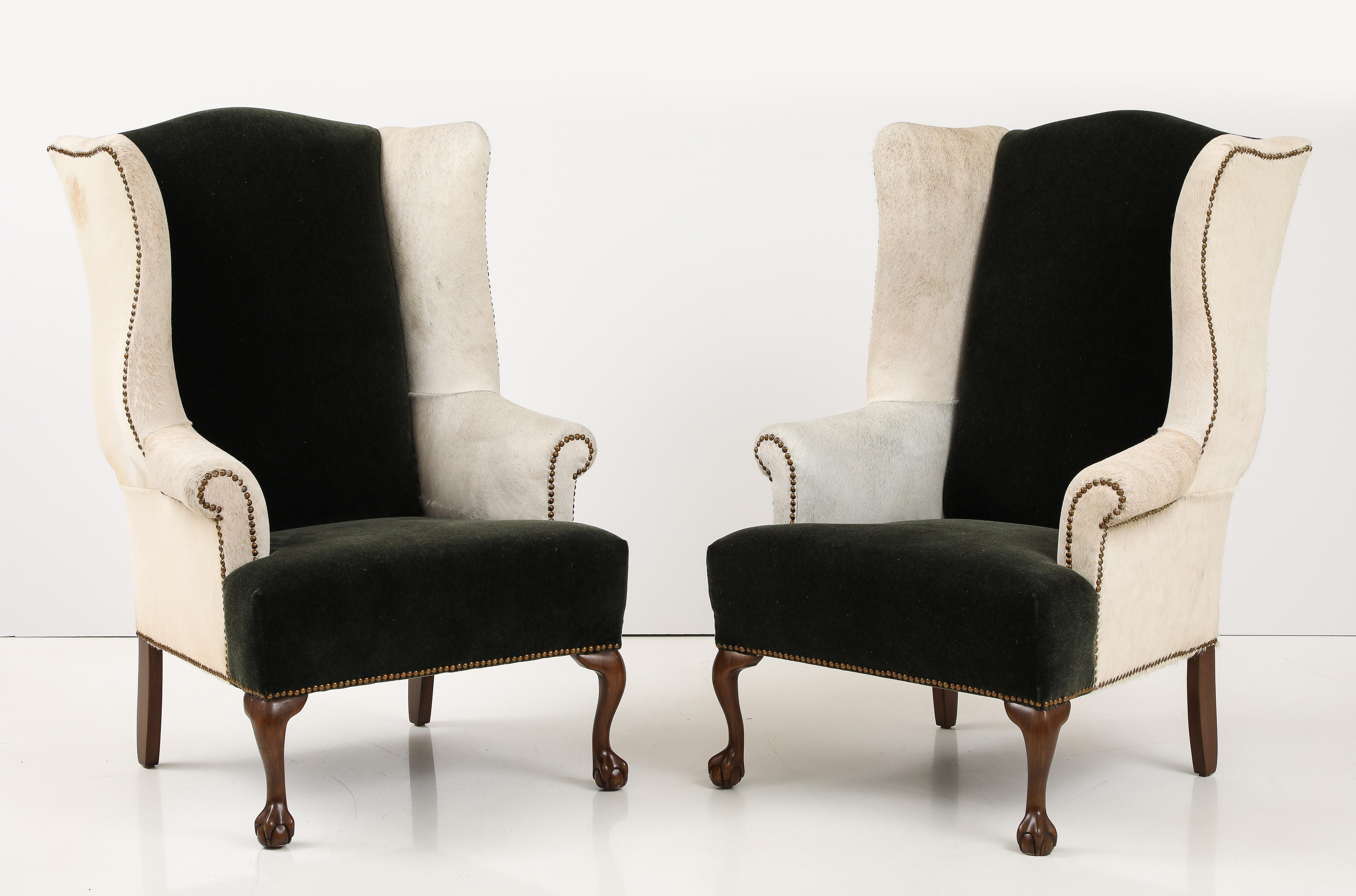 Una coppia di sedie wingback inglesi della fine del XIX secolo sono state rinnovate utilizzando  La nuova tappezzeria in cuoio bianco sporco e mohair verde Jaguar e i piedi a zampa d'elefante in mogano intagliati a mano sono stati riportati al