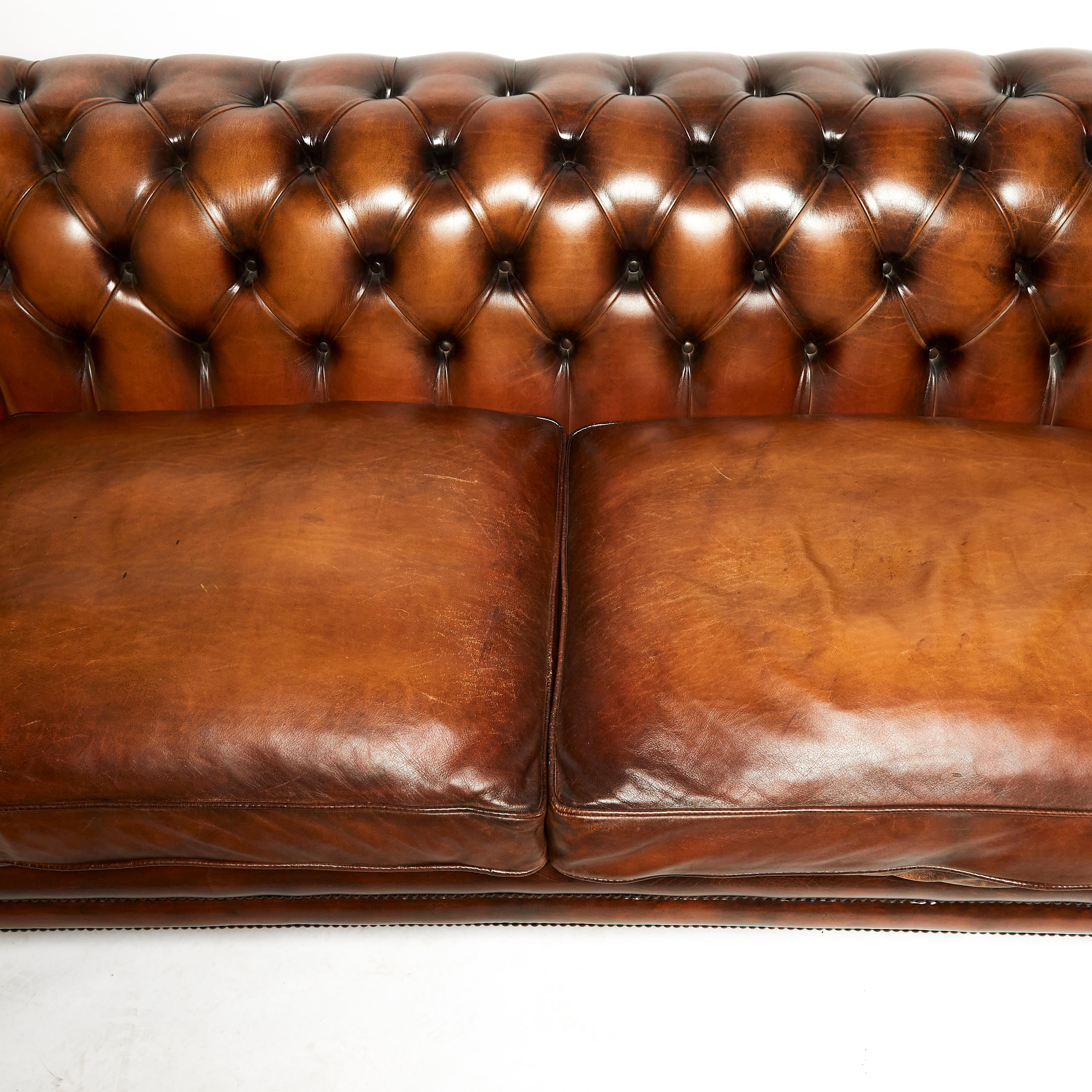 This very good looking and extremely comfortable English chesterfield sofa is made in the traditional 19th century style, standing on front turned and swept back legs. The sofa features 2 separate seat cushions with a generously sized rollback arms