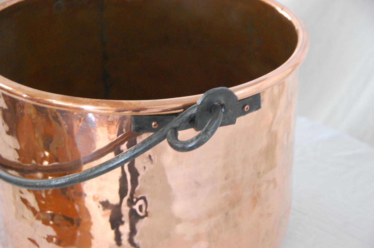 English 19th century large copper cauldron of dovetailed construction, heavy iron swing handle. This cauldron of 16