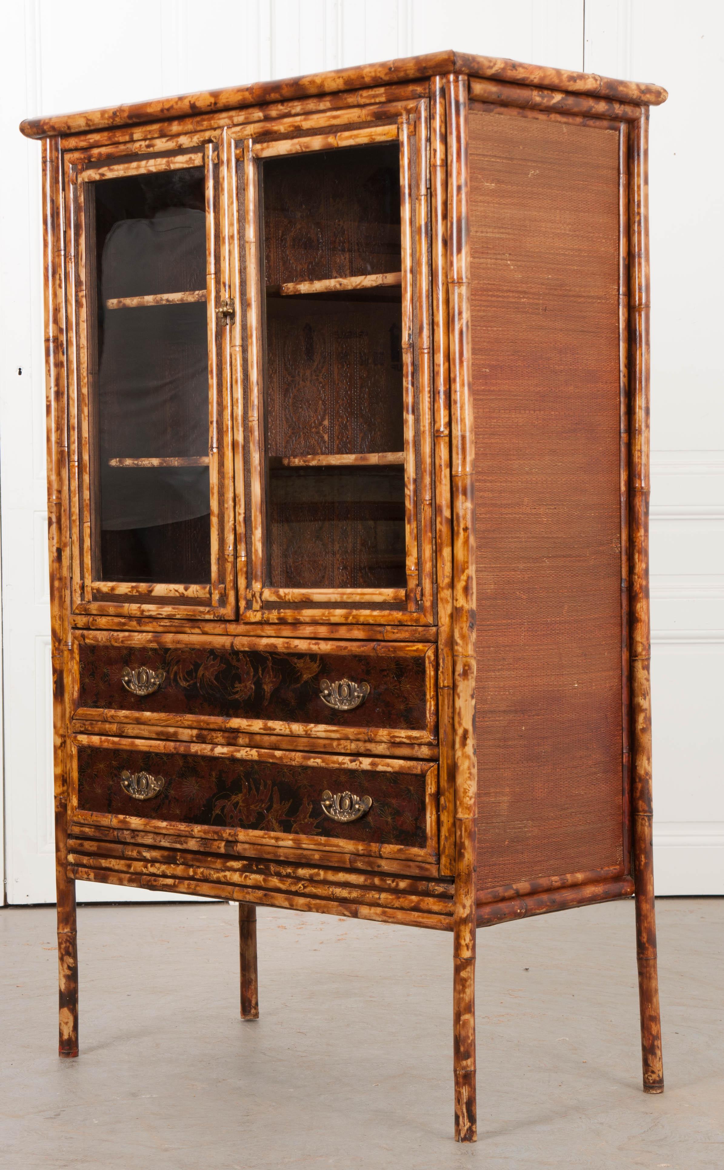 This fabulous example of an Aesthetic Movement faux-tortoise bamboo bookcase, c.1880, is from England. Petite in stature and retaining all of the original components, this piece features a pair of glazed door that reveal a pair of shelves, entirely