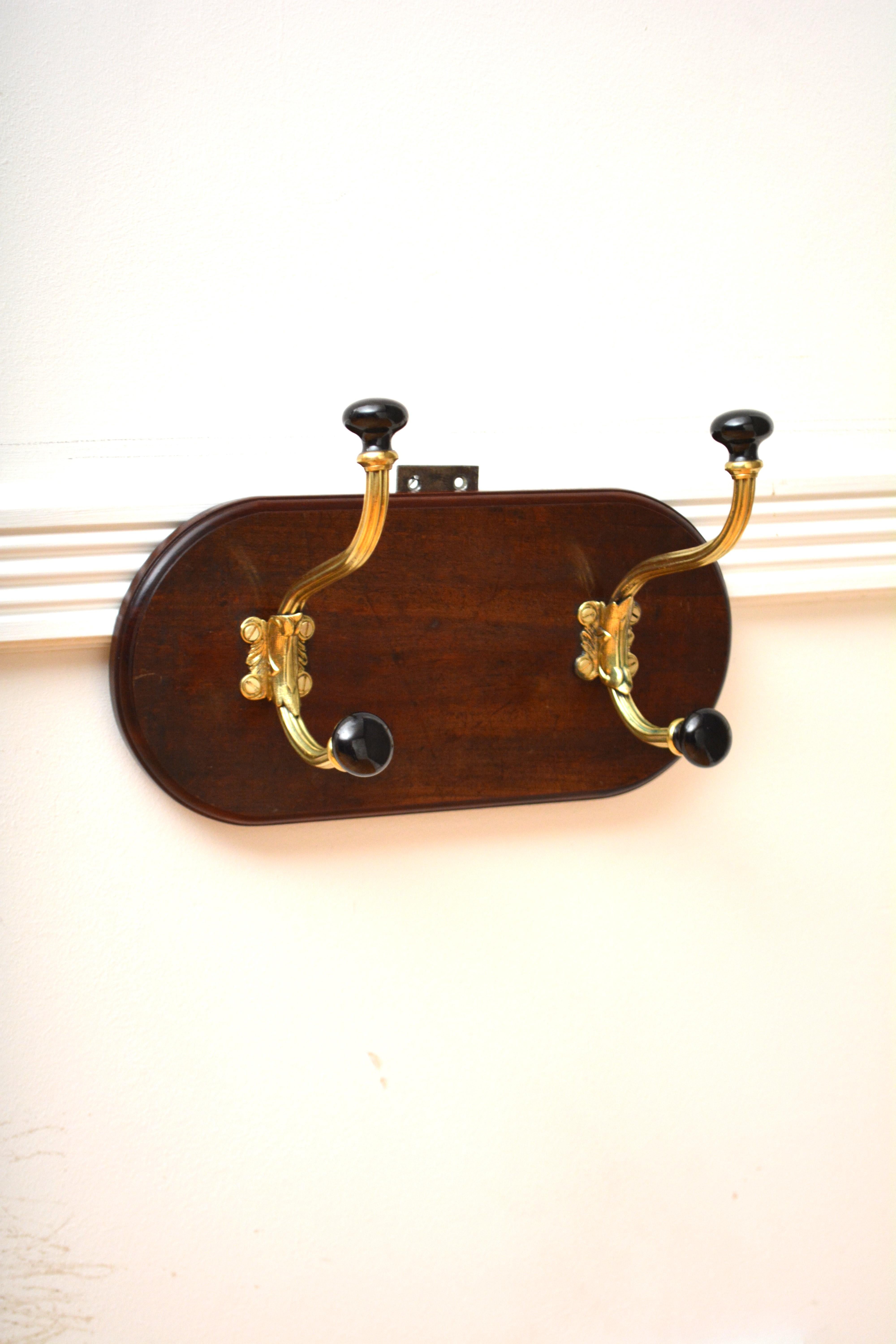 P0313 Superb English  Set di due ganci per cappelli e cappotti in ottone lucido e scanalato con estremità in ceramica nera del XIX secolo su un supporto in mogano massiccio con bordo modellato. Questo appendiabiti d'epoca è pronto per la casa. 
H8