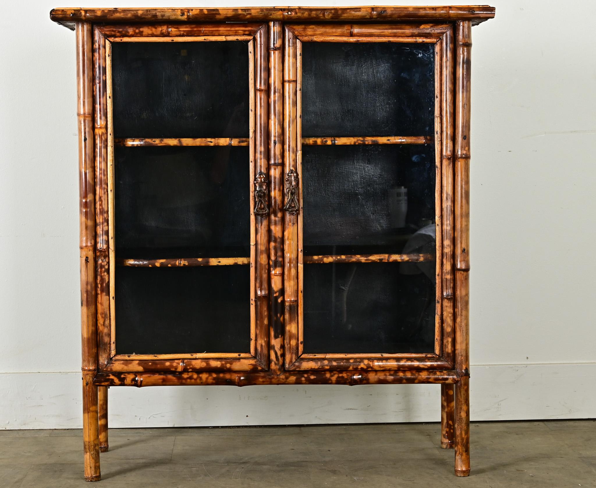 This English Victorian bookcase was given a whimsical update with recent decoupage and ebonized (painted) finish. Schools of fish animate the exterior surfaces, their glowing honey color matching the natural tone of the bamboo frame. Glass-front