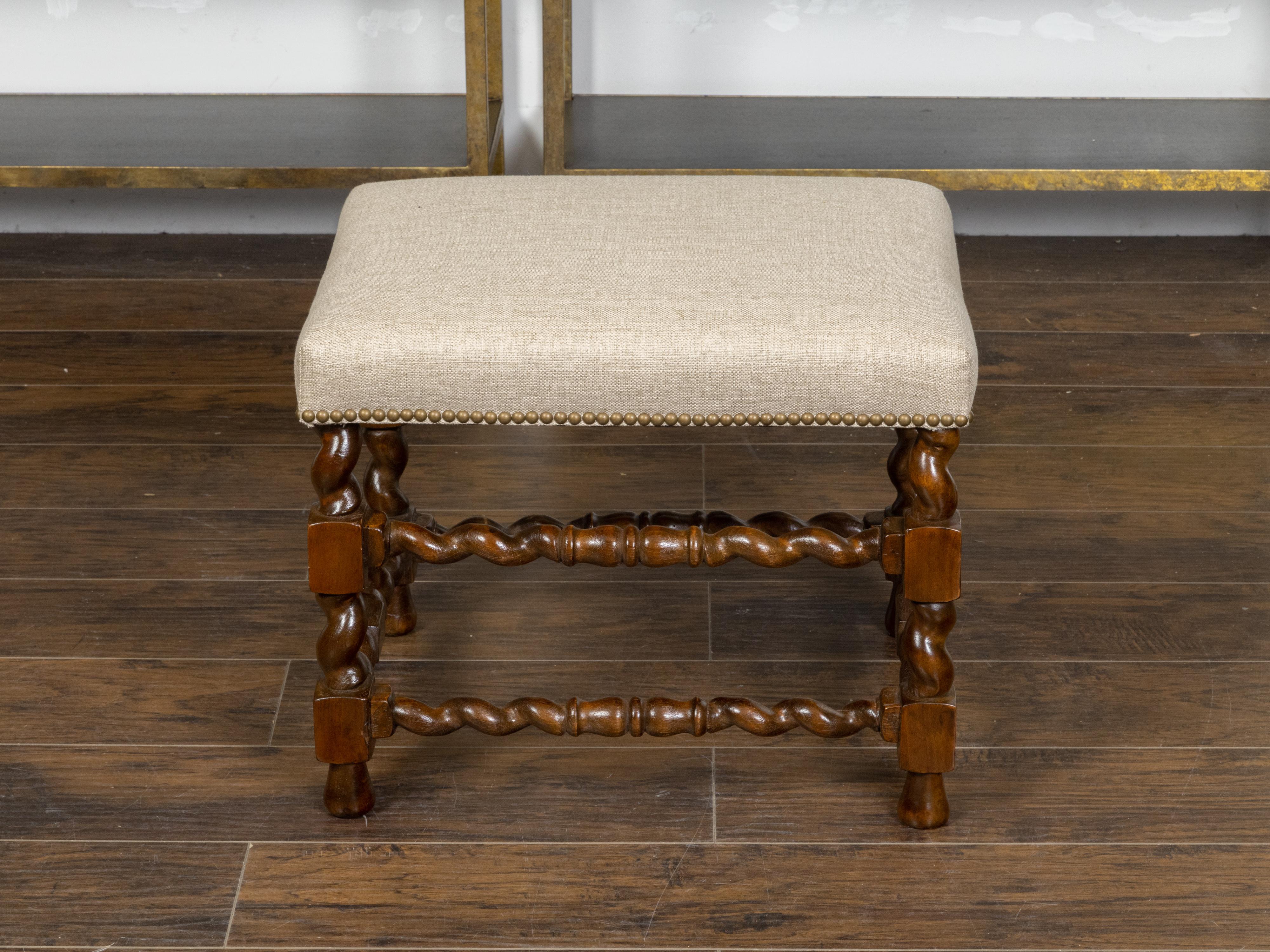 An English oak stool from the 19th century, with barley twist base, rectangular block joints and new linen upholstery and brass nailhead trim. Created in England during the 19th century, this oak stool features a rectangular seat newly recovered