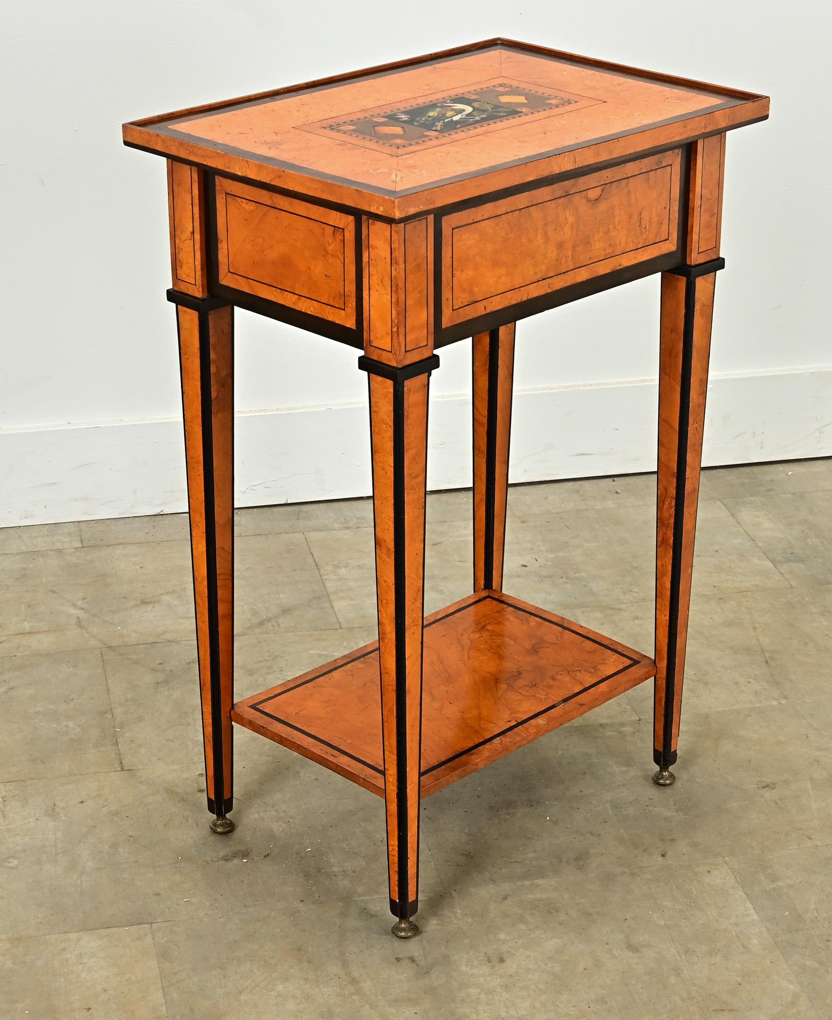 Une intéressante table d'appoint en bouleau des années 1800. Le plateau est orné d'un cartouche en marqueterie colorée représentant un oiseau sur une branche. La marqueterie se compose de plusieurs types de marbre, de bois de satin et d'ébène. Les
