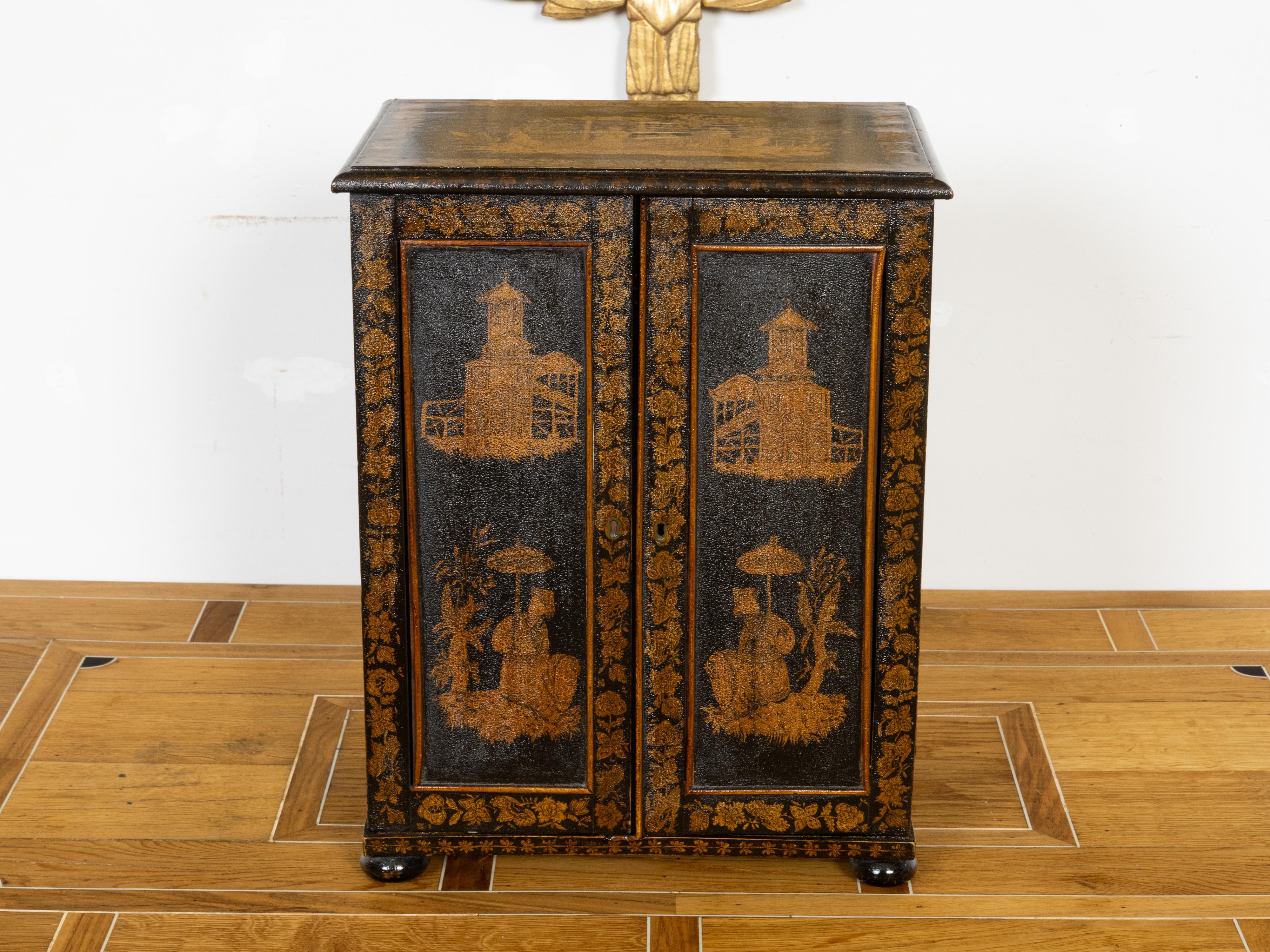 A small English black and gold cabinet from the 19th century, with chinoiserie décor, two doors and seven inner graduated drawers. Created in England during the reign of Queen Victoria in the 19th century, this small table top cabinet features a