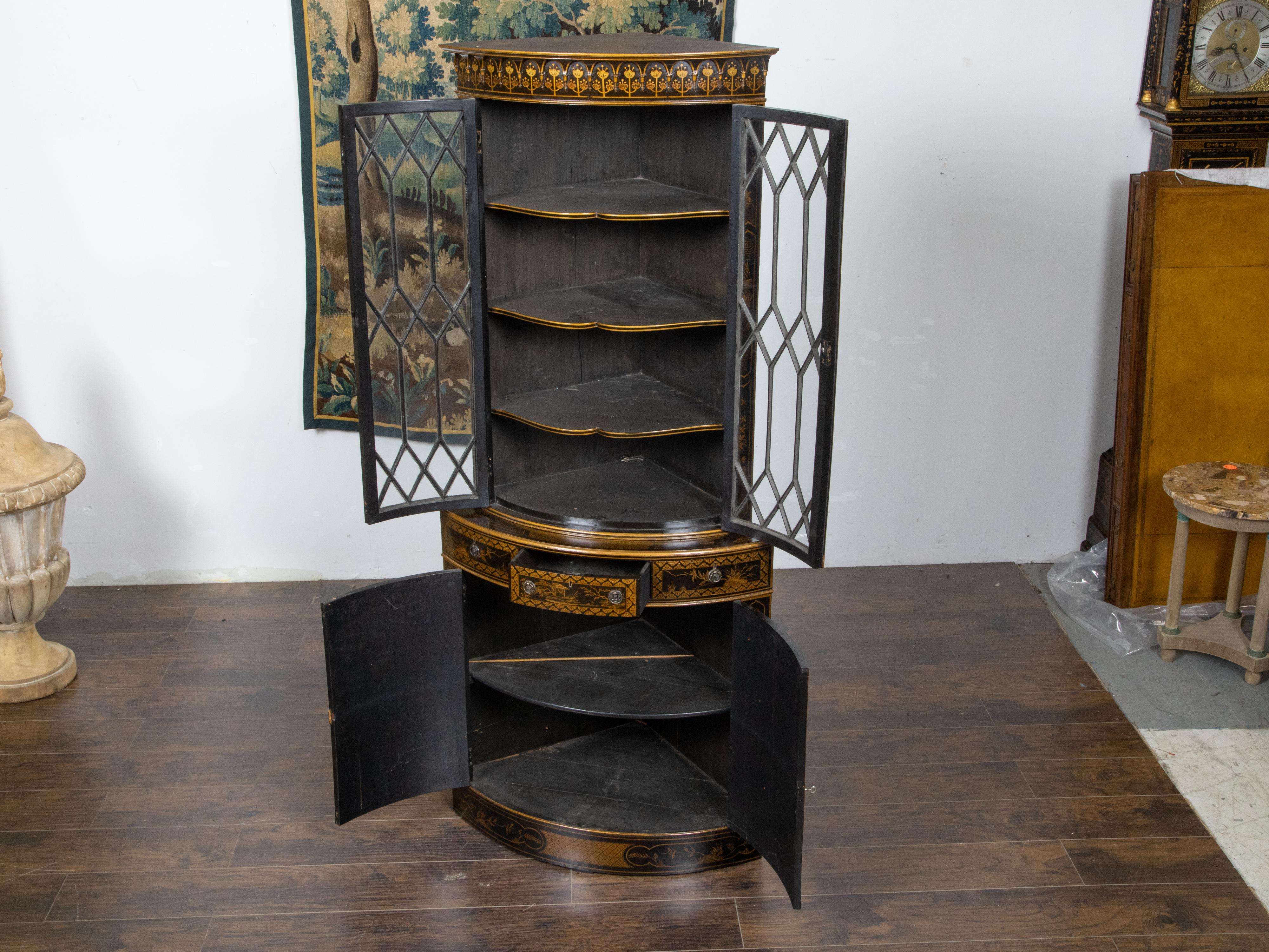 An English black and gold corner cabinet from the 19th century, with paneled glass doors, three middle drawers and Chinoiserie décor. Created in England during the 19th century, this corner cabinet attracts the attention with its complimenting