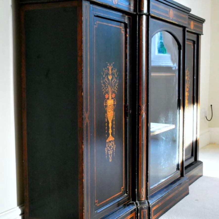 Lovely original English late Victorian breakfront black lacquered breakfront credenza with marquetry and twist brass work and original glass to the centre door. Inlaid with burr walnut and boxwood.
Good decorative piece of furniture and will work