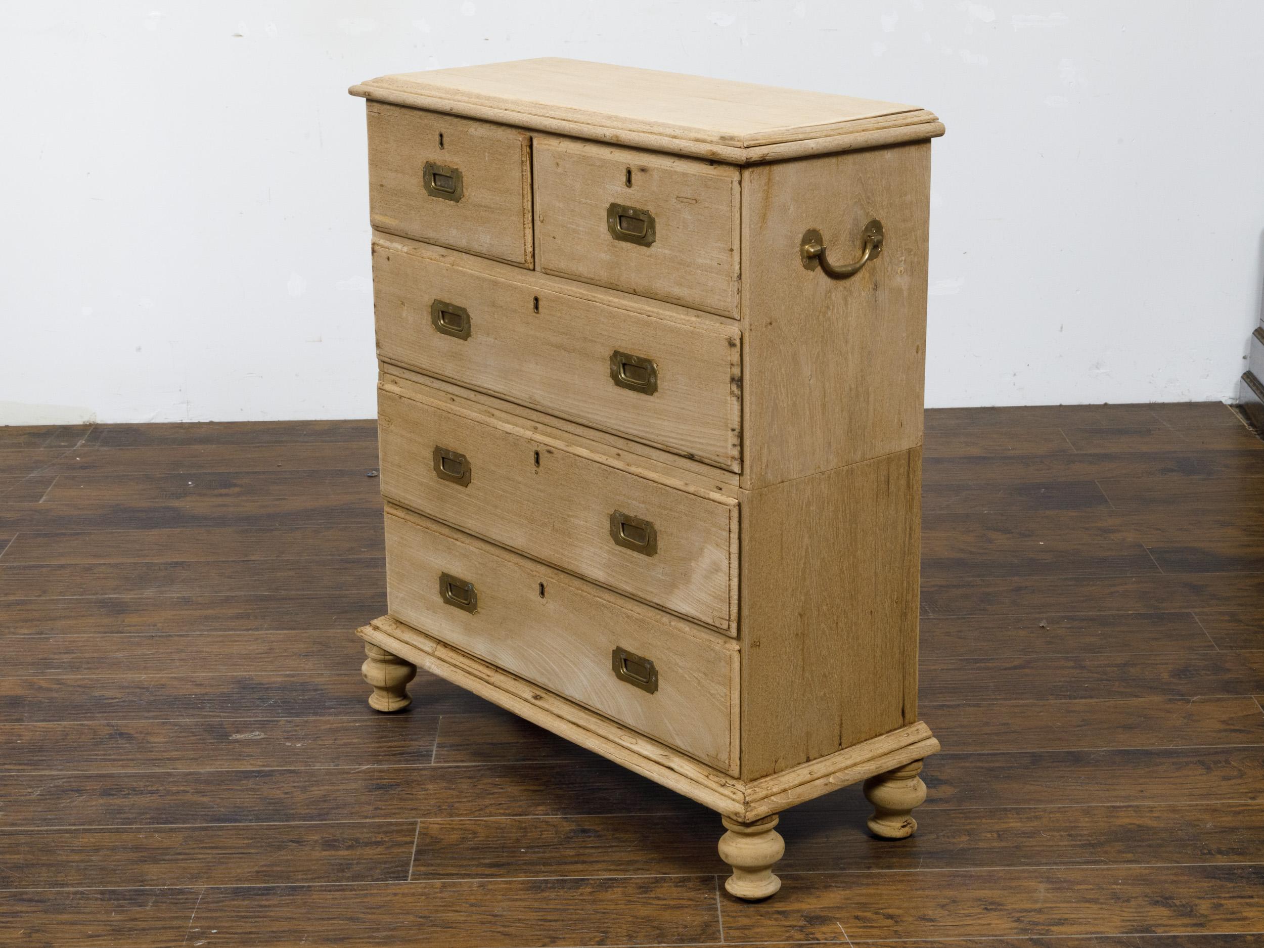 An English bleached wood two-part chest from the 19th century with five drawers, inset brass hardware and turned feet. This English two-part chest, crafted in the 19th century, embodies a blend of classic elegance and subtle rustic charm. Featuring