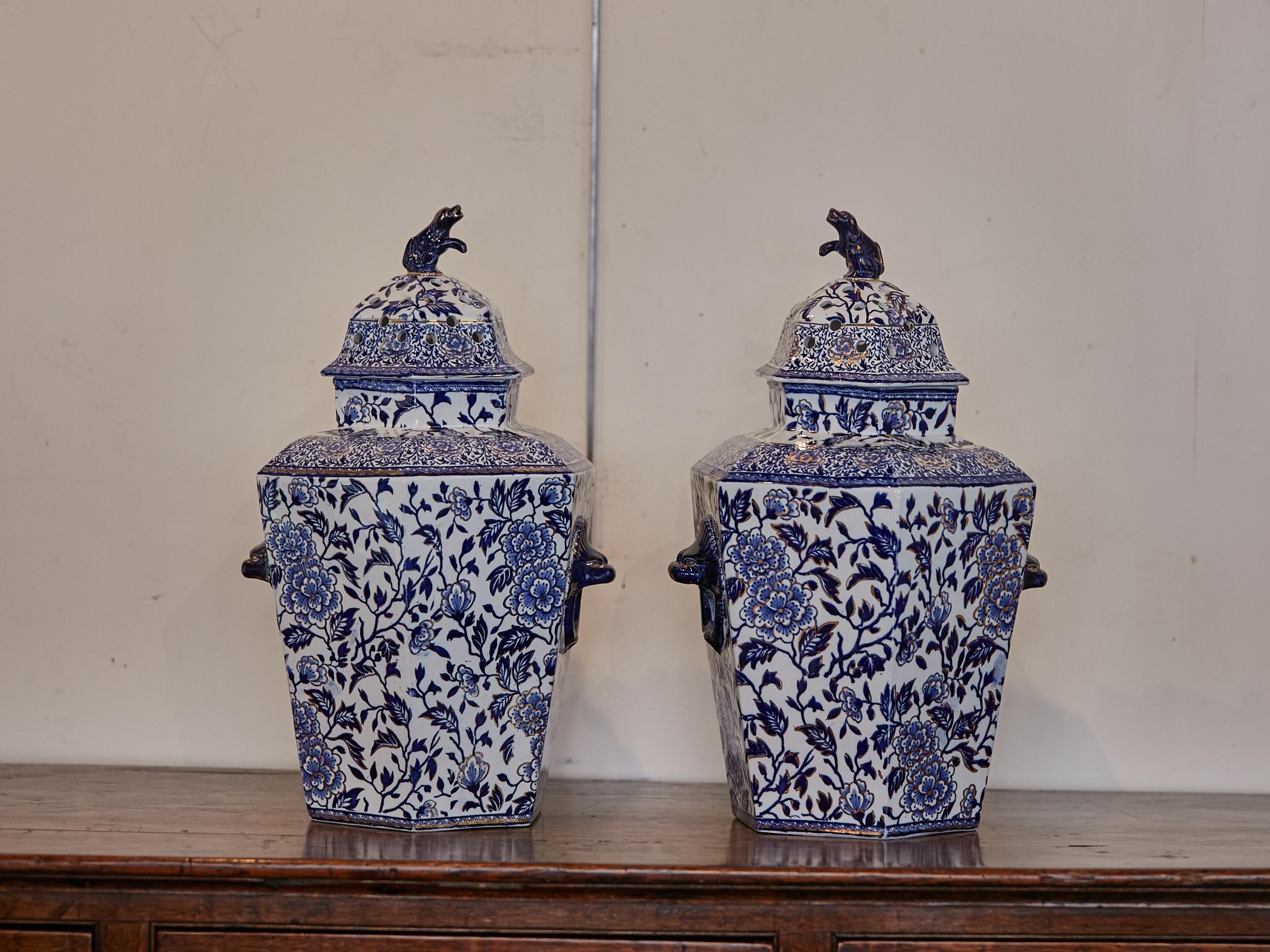 A pair of English blue and white porcelain lidded hexagonal pot pourri pots from the 19th century with dog finials. Embrace the elegance of Chinoiserie with this exquisite pair of English blue and white porcelain lidded hexagonal pot pourri pots